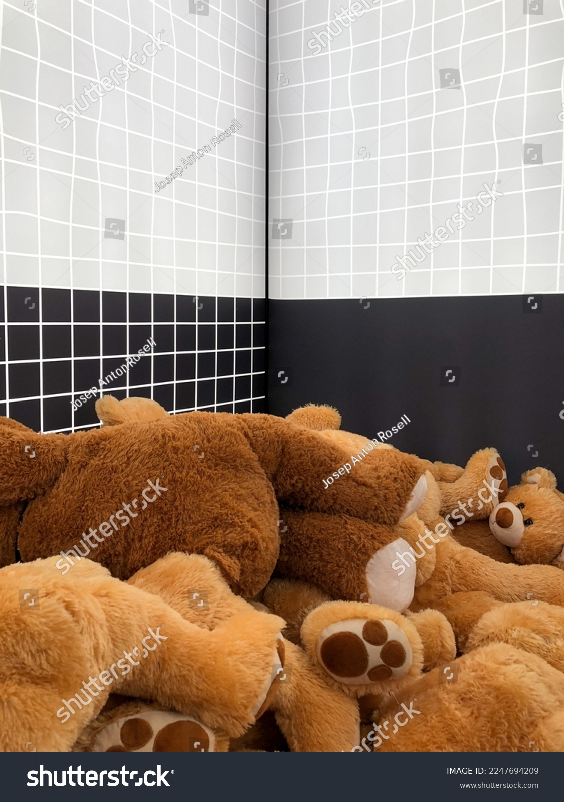 A lot of teddy bears inside a white and black room. Many fluffy bears stretched out on the floor in a room. Brown toy bears on the ground. #2247694209