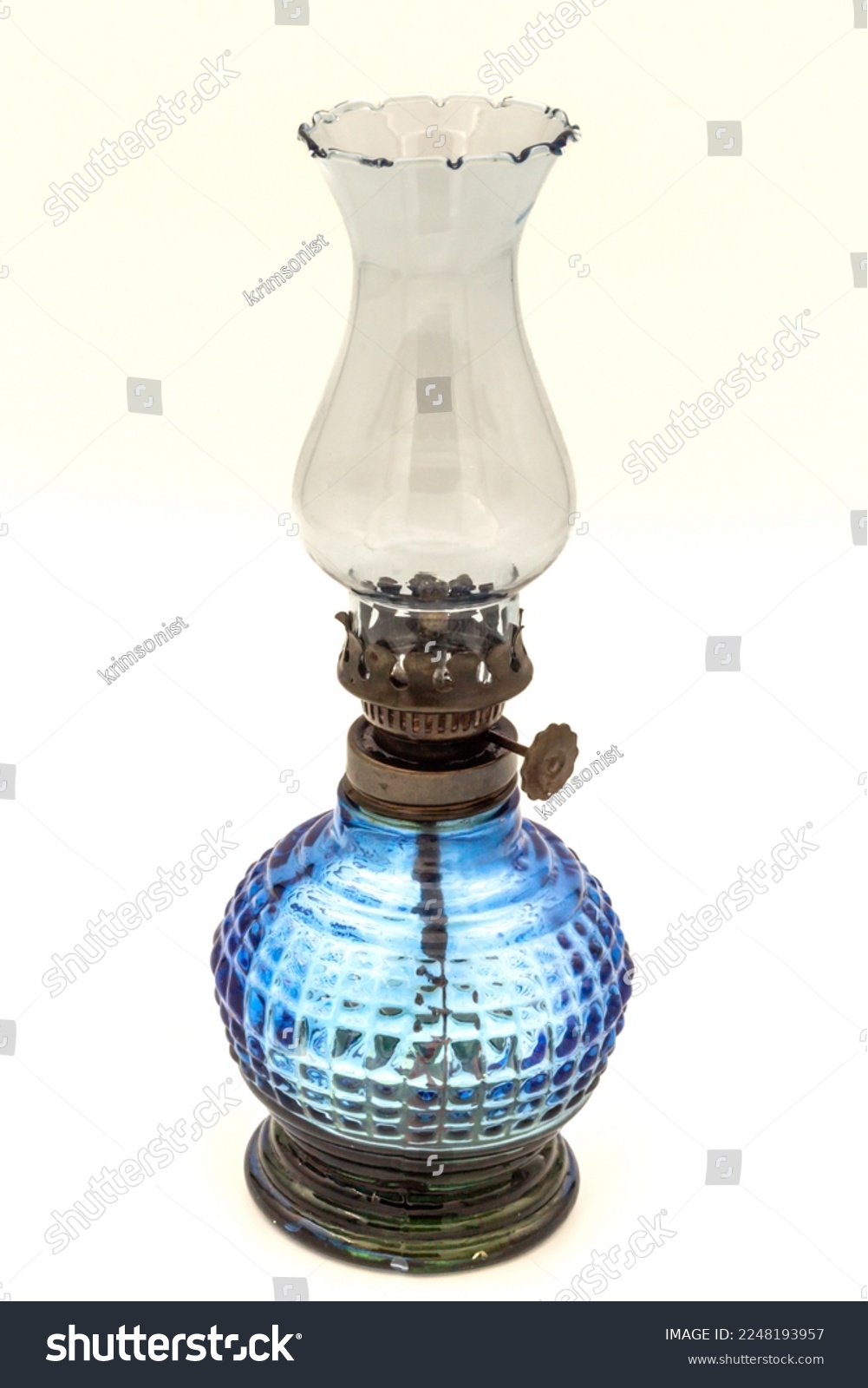 Blue colored glass oil lamp with old weathered and rusted glass. Close-up, on a white background. #2248193957
