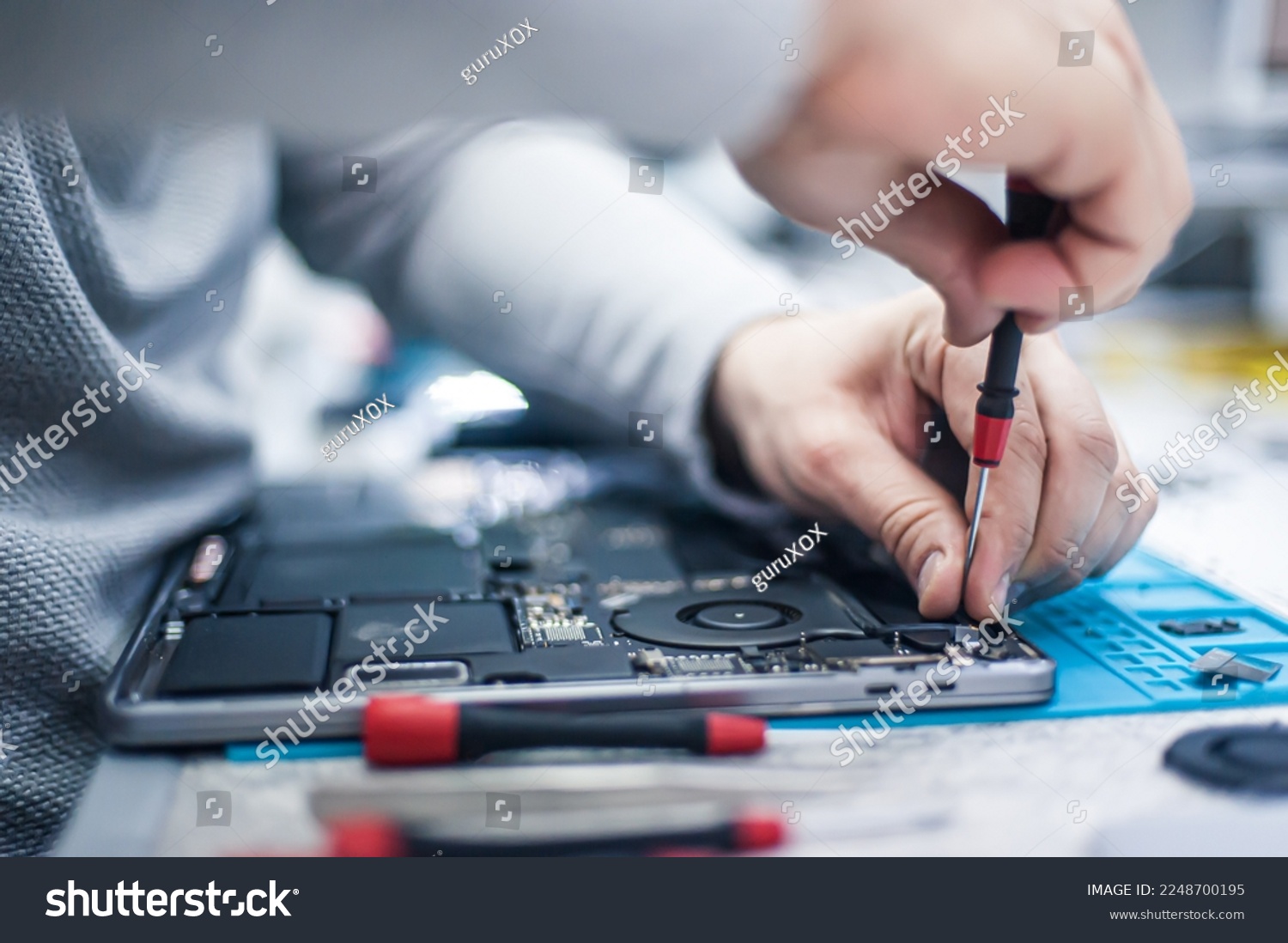 Technical support and fixing gadgets problems. Servicing, repairing, cleaning, maintaining computers. Repair shop. Hardware maintenance. Male technicians fixing disassembled laptop parts.  #2248700195