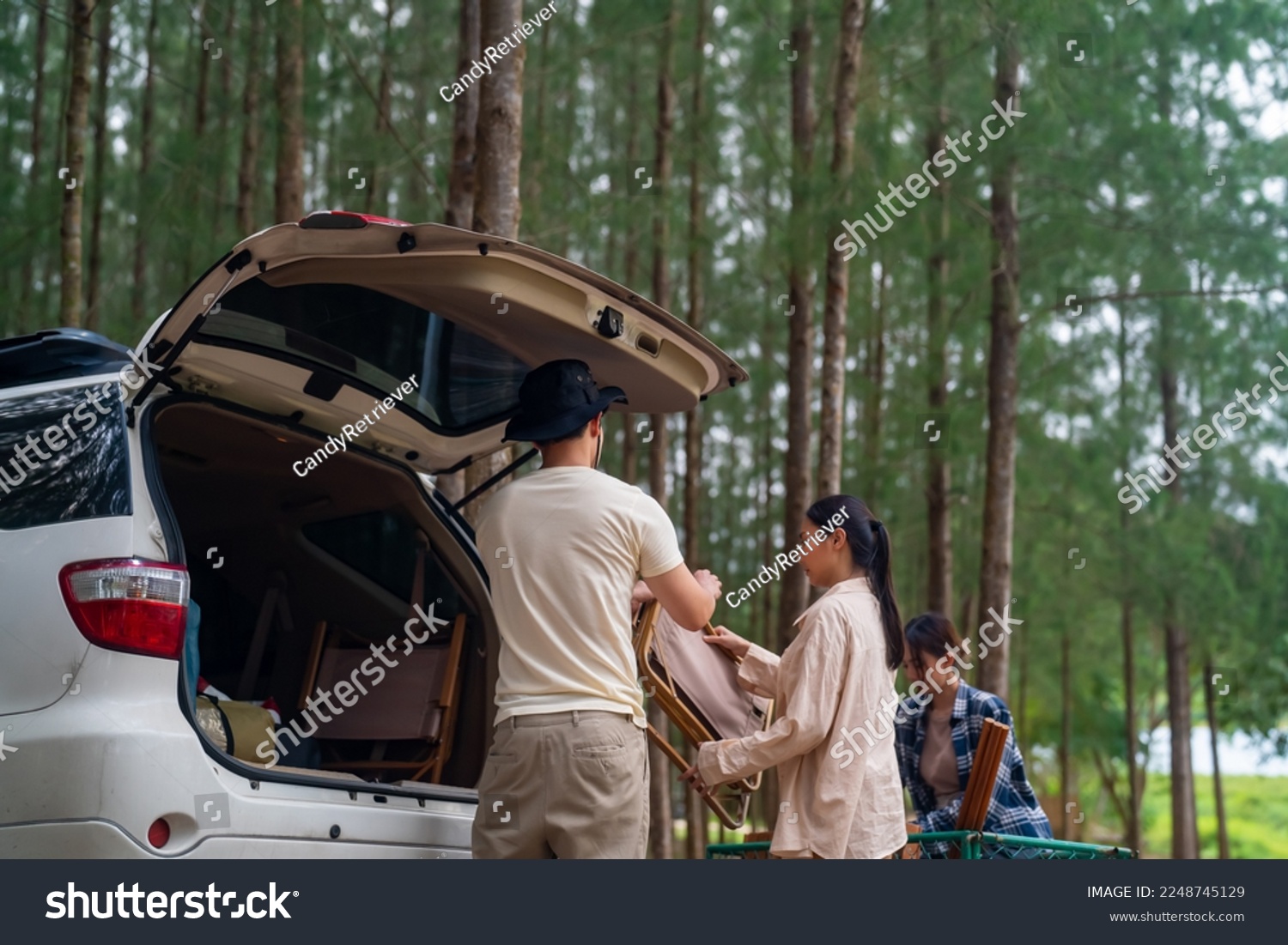 Group of Asian people friends enjoy outdoor lifestyle road trip and camping together on summer holiday travel vacation. Man and woman taking off camping supplies from car trunk at natural park. #2248745129