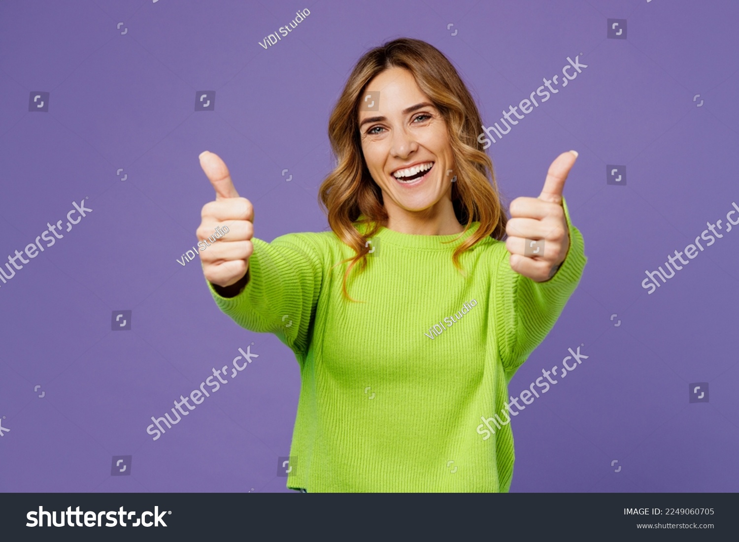 Young smiling fun cool positive woman 30s she wearing casual green knitted sweater showing thumb up like gesture isolated on plain pastel purple background studio portrait. People lifestyle concept #2249060705