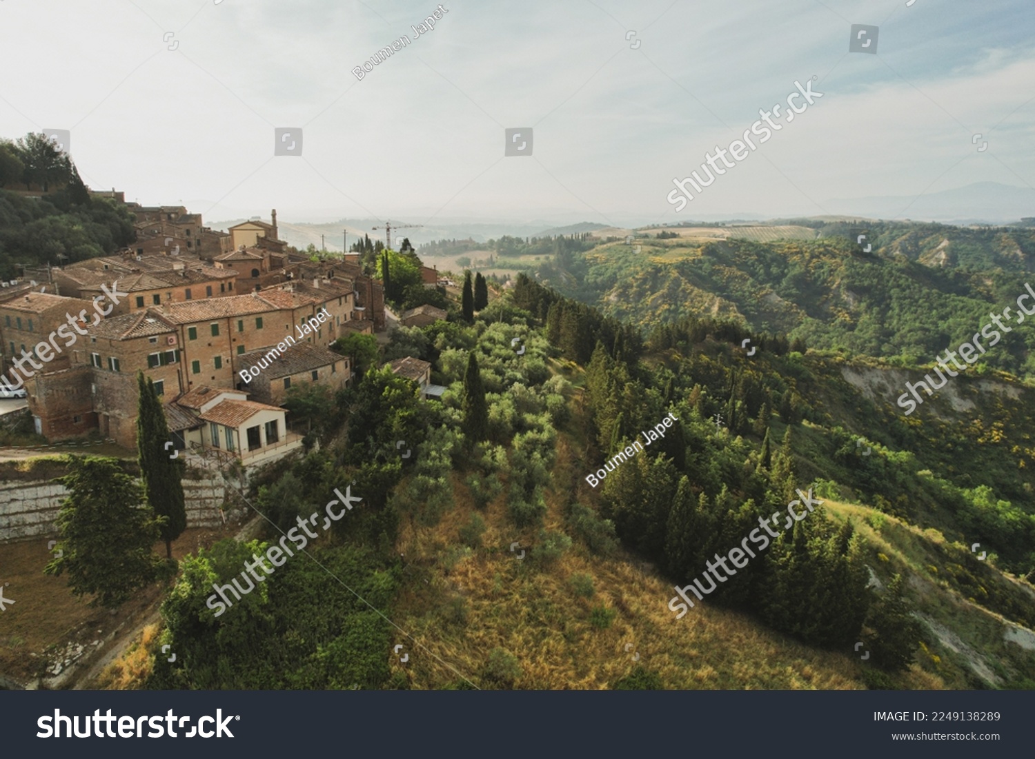 Small village of Chiusure on top of the hill surrounded by Karst cliffs landscape photographed with a drone. Toscana, Tuscany, Asciano, province of Siena in Italy with a little mud road 06.16.2021 #2249138289
