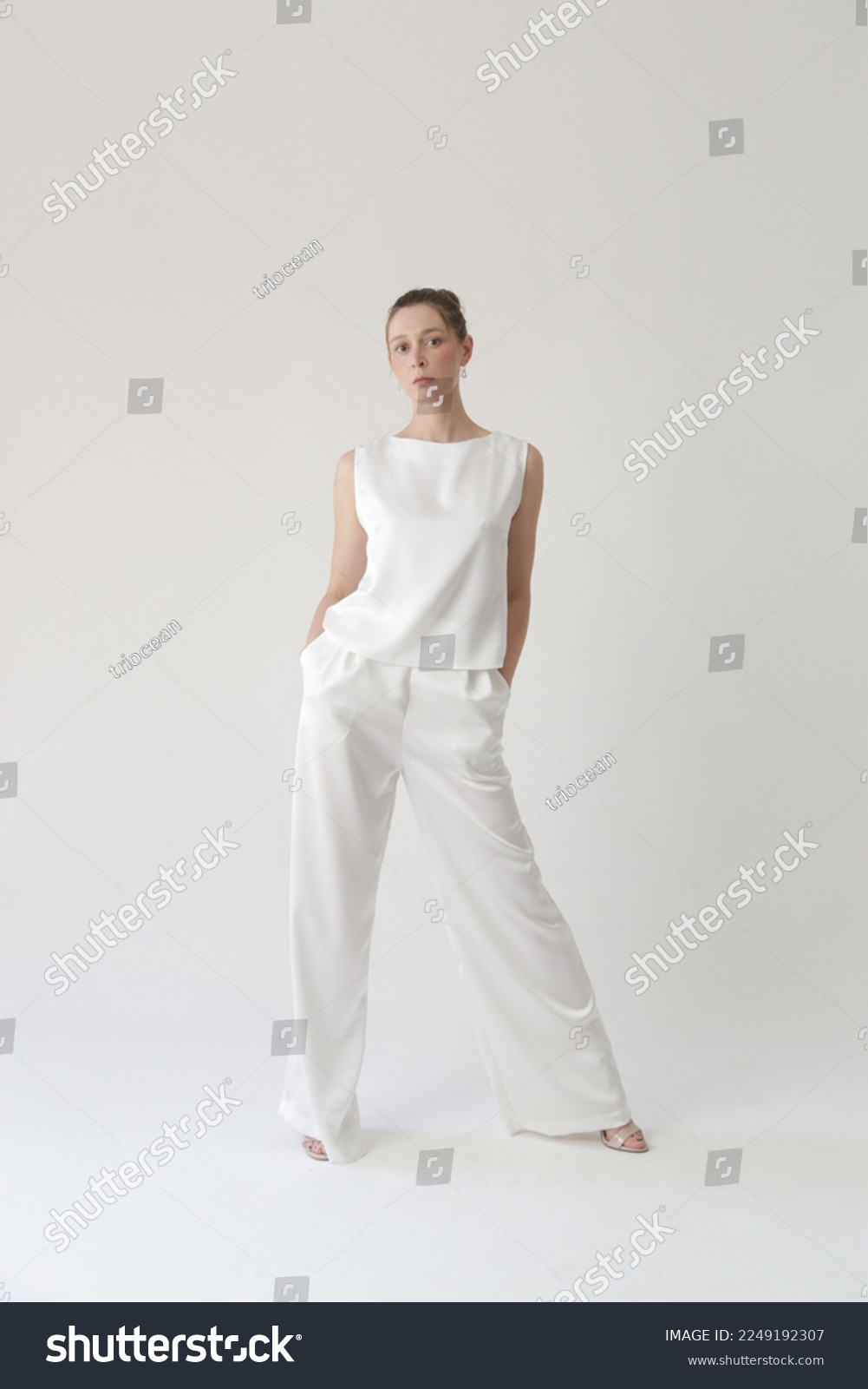 Serie of studio photos of young female model in all white silk outfit, sleeveless blouse and wide legs trousers	 #2249192307
