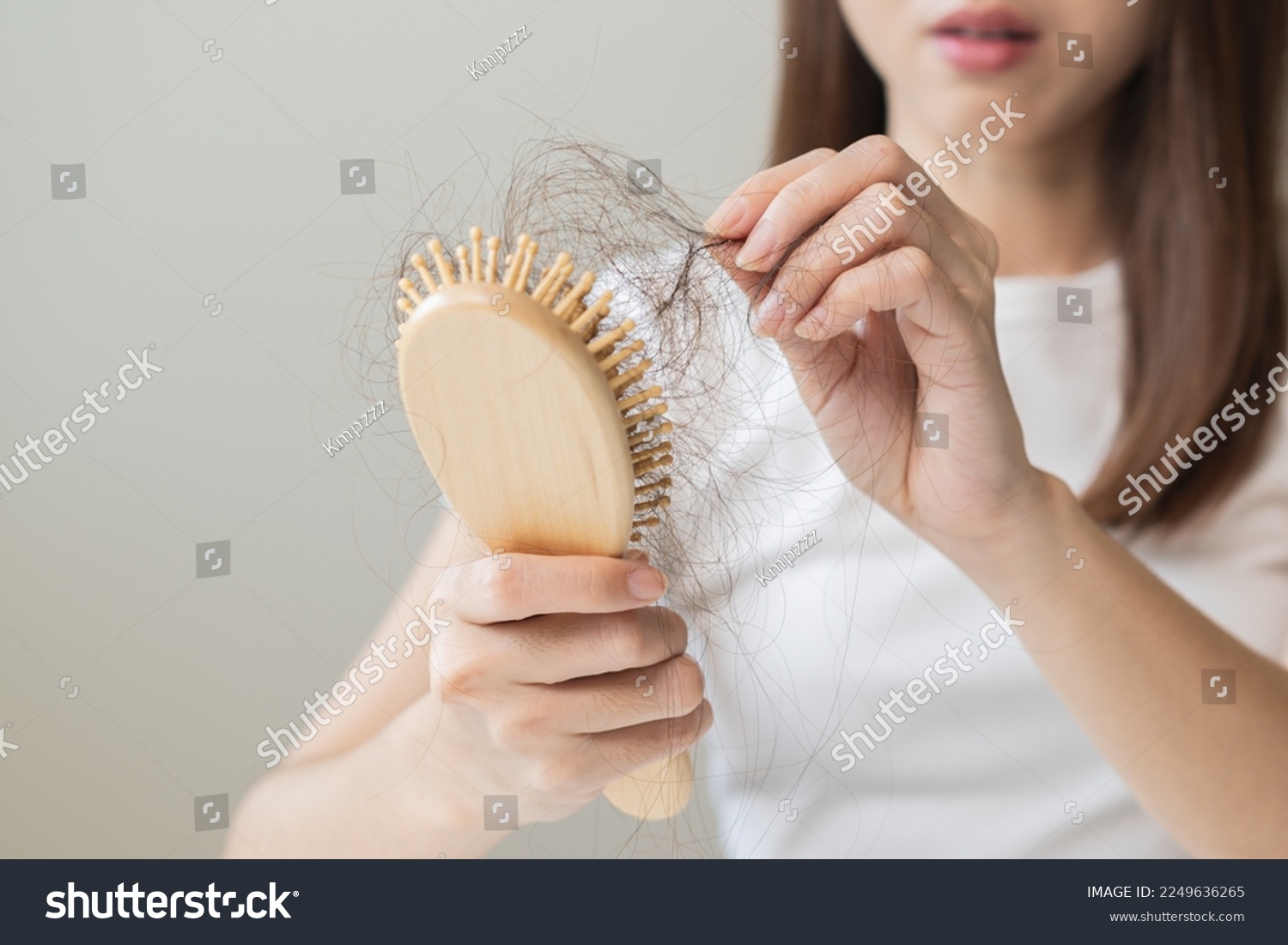 Serious asian young woman holding brush holding comb, hairbrush with fall black hair from scalp after brushing, looking on hand worry about balding. Health care, beauty treatment, hair loss problem. #2249636265