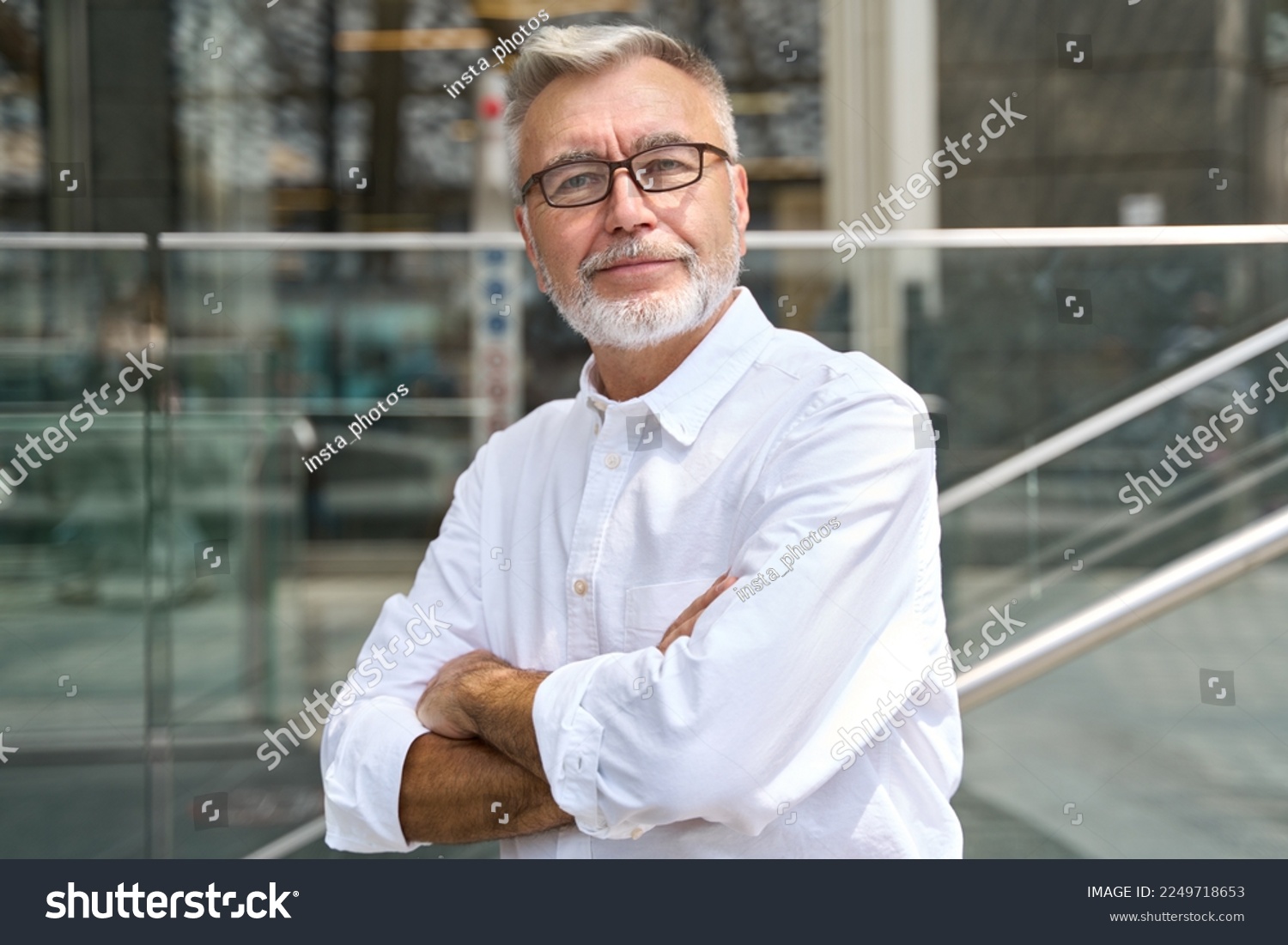 Confident happy mature older business man leader, smiling middle aged senior old professional businessman wearing white shirt glasses crossed arms looking at camera standing outside, portrait. #2249718653