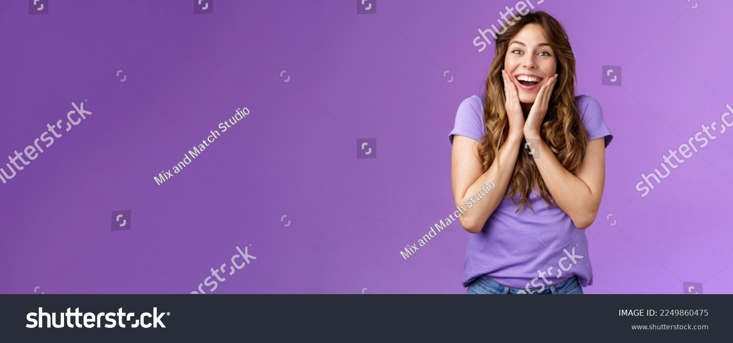 Happy lively lucky enthusiastic girl curly hairstyle open mouth admiration fascinated smiling broadly touch cheek impressed surprised awesome incredible positive news stand purple background. #2249860475