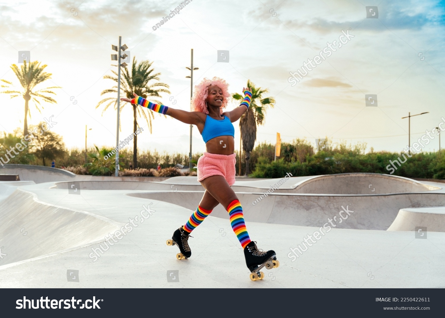 Beautiful woman skating with roller skates and having fun. Professional skater and dancer training in the morning wearing colored and fashionable clothes. #2250422611