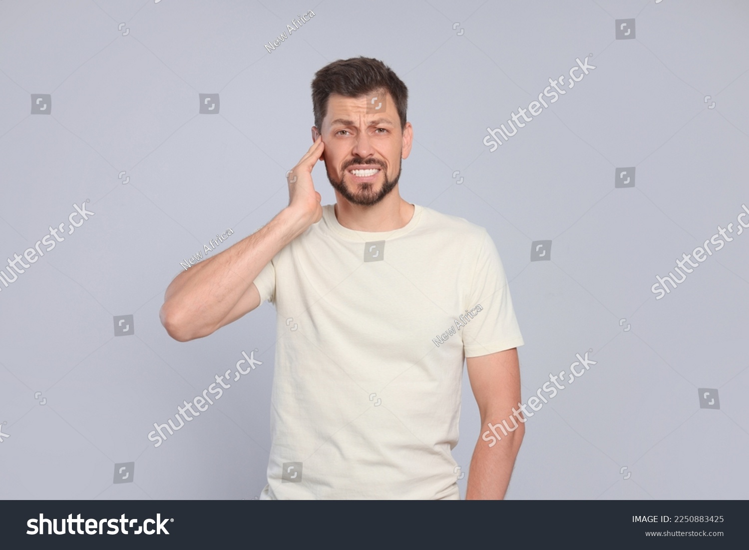 Man suffering from ear pain on grey background #2250883425