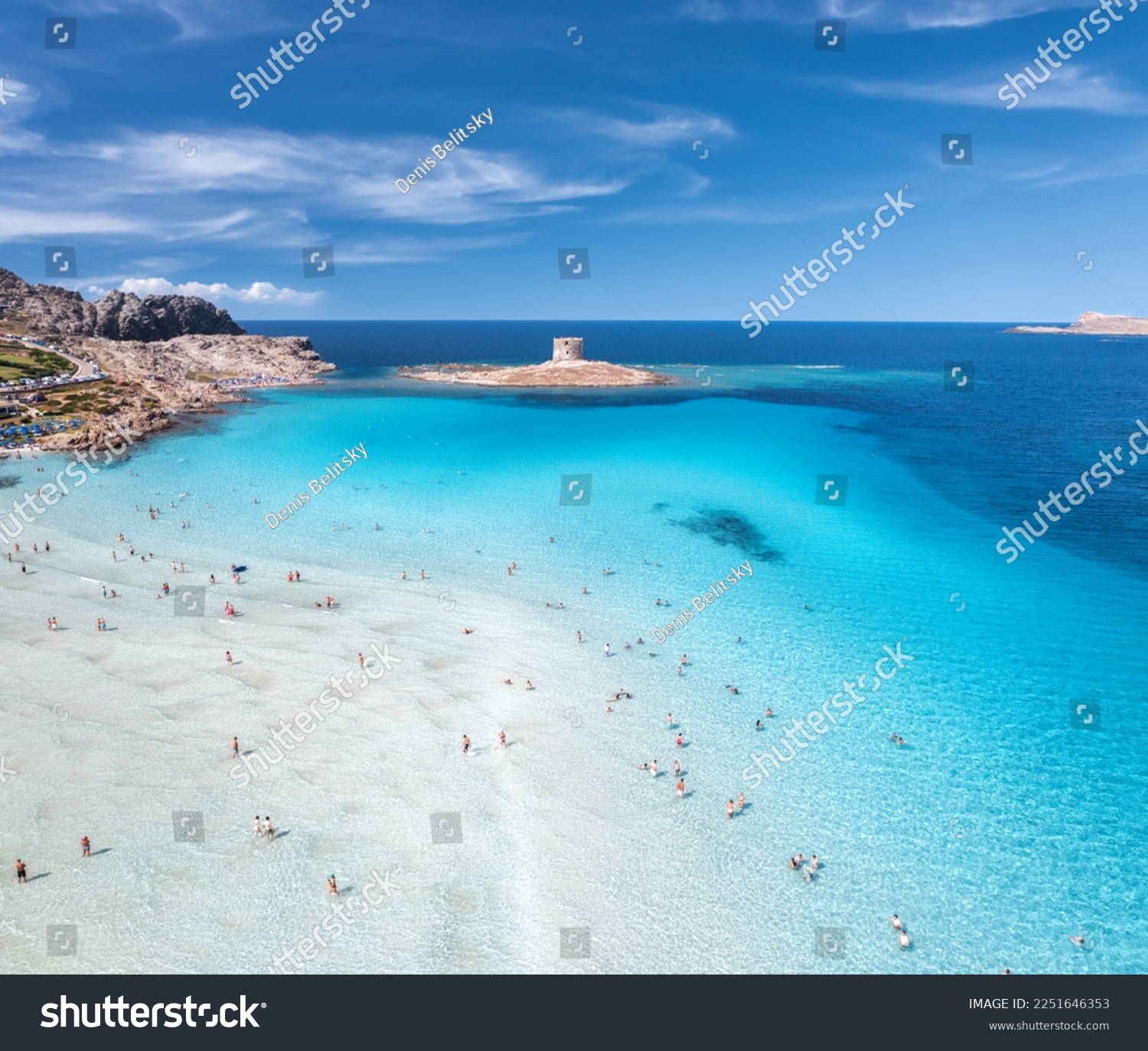 Aerial view of famous La Pelosa beach at sunny summer day. Stintino, Sardinia island, Italy. Top view of sandy beach, swimming people, clear blue sea, old tower and sky with clouds. Tropical seascape #2251646353