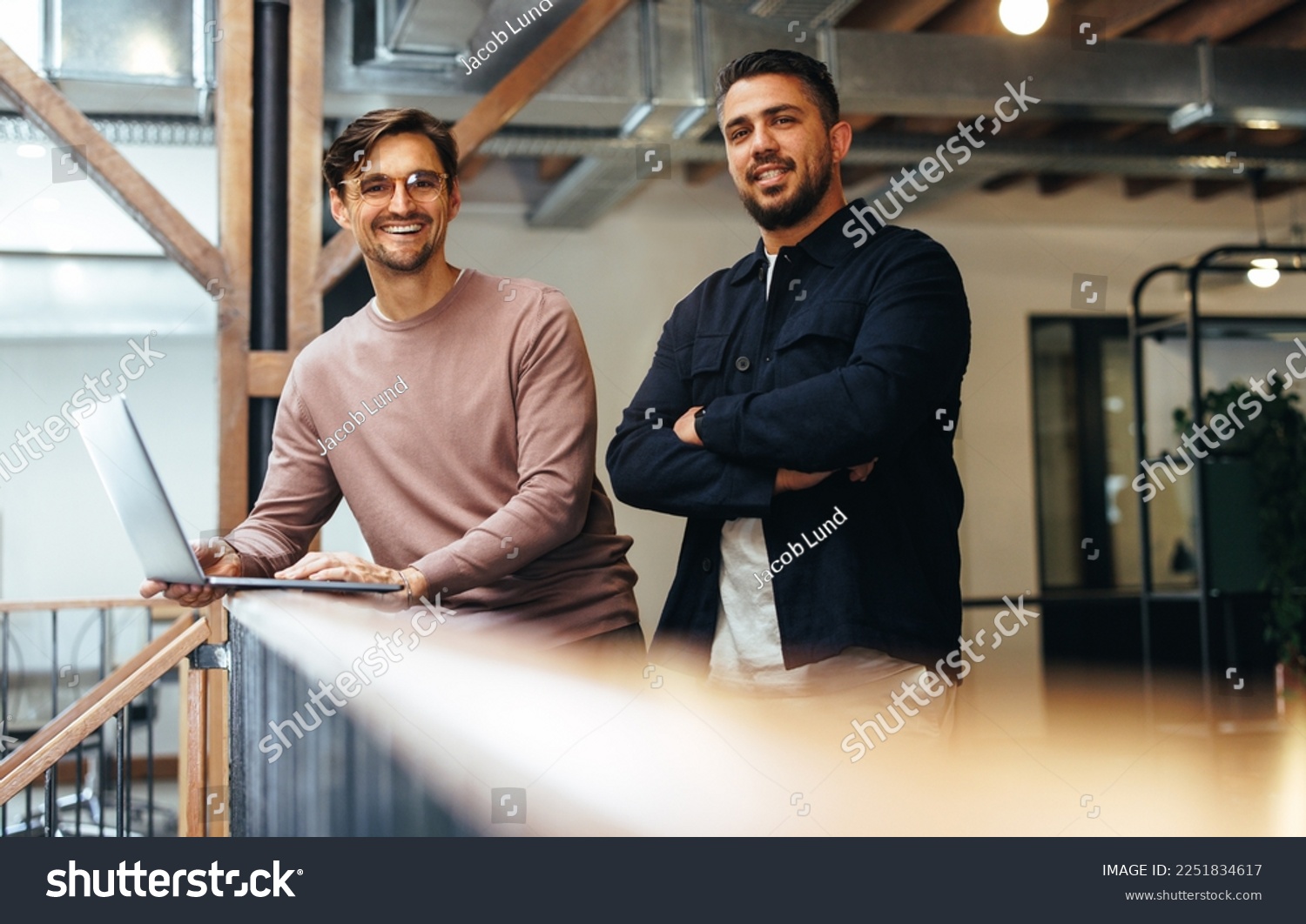 Male business professionals standing on an interior balcony and looking at the camera. Two business men working together in a tech startup. #2251834617