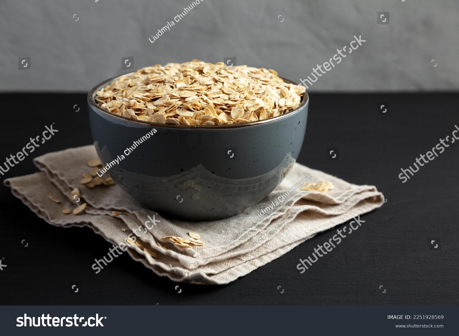 Wholegrain Oat Flakes in a Bowl on a black background, side view.  #2251928569