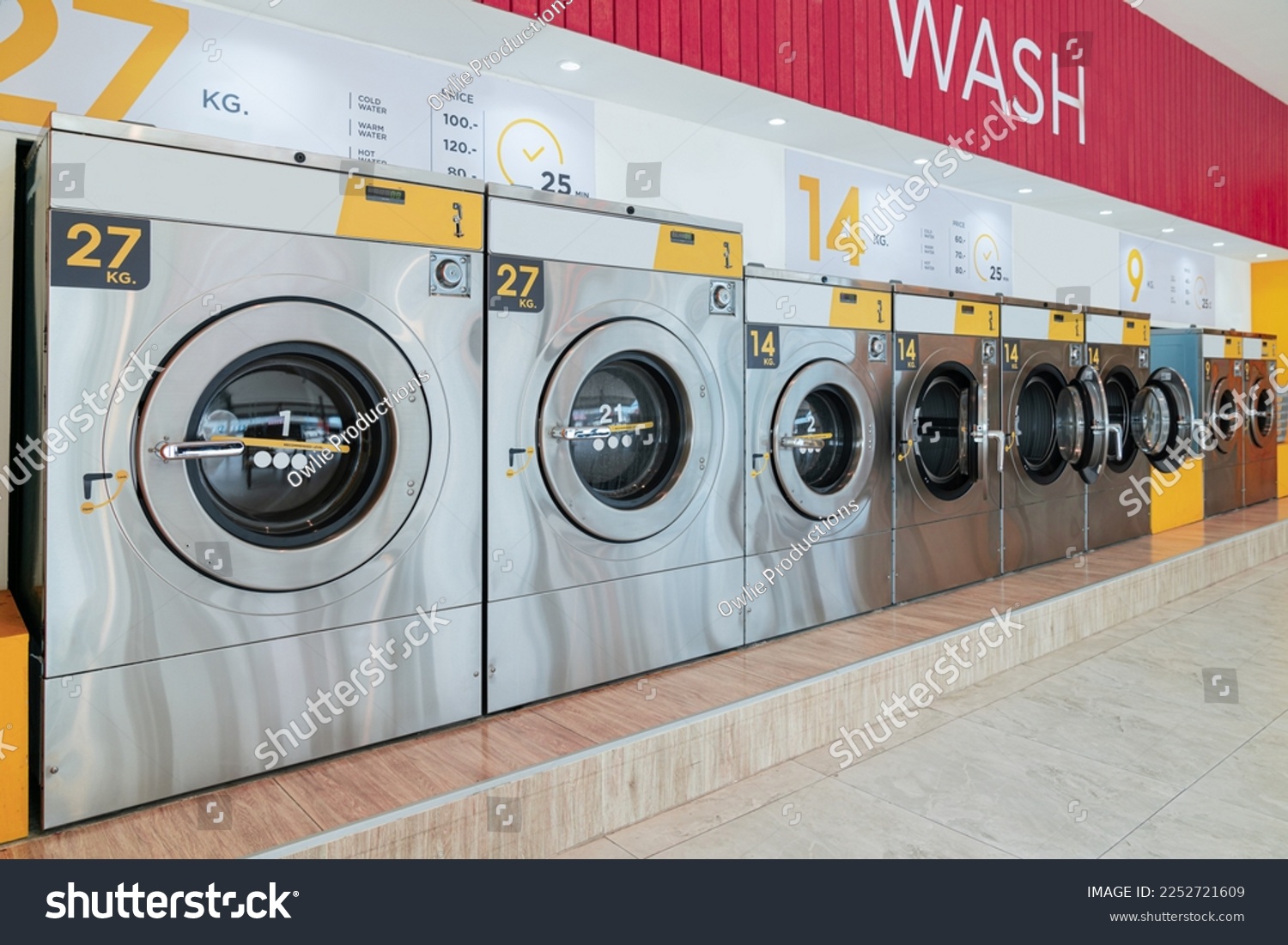 A row of qualified coin-operated washing machines in a public store. Concept of a self service commercial laundry and drying machine in a public room. #2252721609