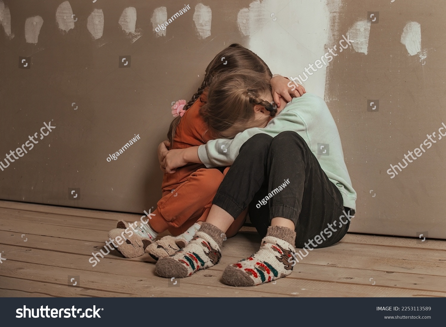 two little sister girls hugged and crying in the attic of the house, they are scared. domestic violence and a dysfunctional family with underage children #2253113589