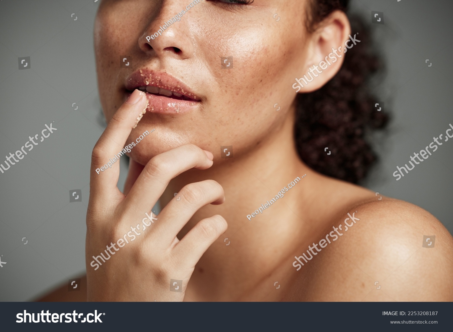 Woman, hand and lips in sugar scrub for skincare, makeup or cosmetics against a grey studio background. Happy female applying treatment for facial cosmetic, lip dermatology or mouth exfoliation #2253208187