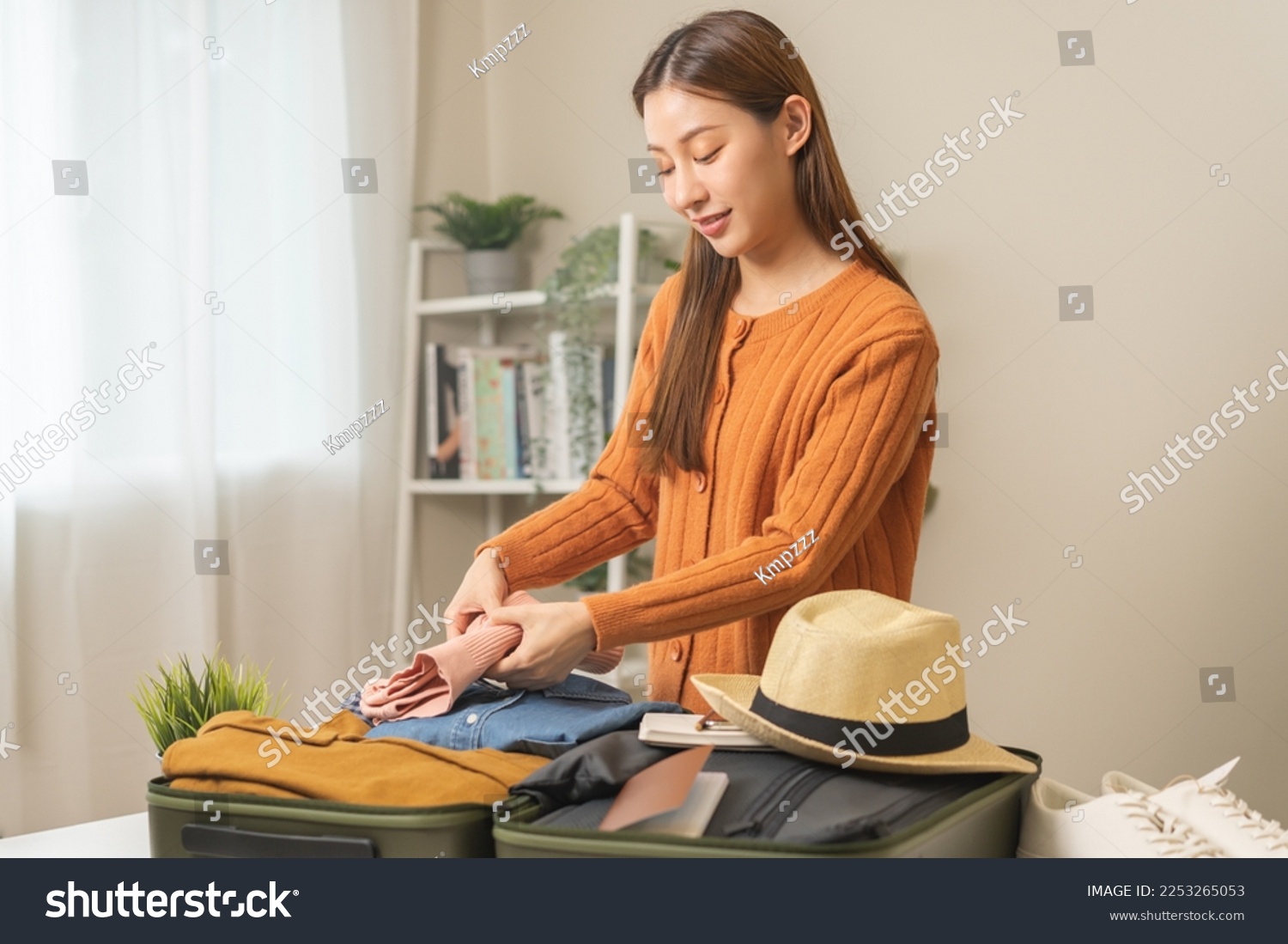 Vacation, holiday travel, traveler asian young woman, girl hand folding clothes packing and preparing stuff into luggage or baggage bag case for journey trip, preparation for journey voyage at home. #2253265053