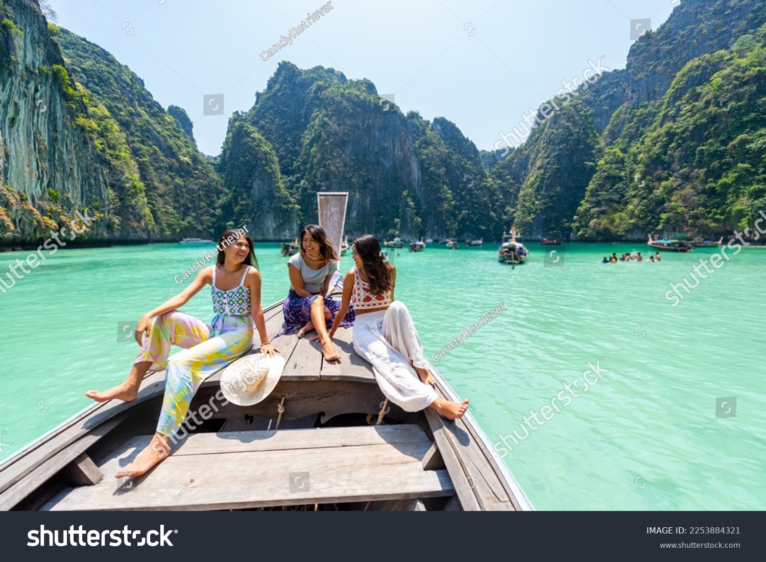 Group of Young Asian woman friends sitting on the boat passing island beach lagoon in summer sunny day. Attractive girl enjoy and fun outdoor lifestyle travel on summer holiday vacation in Thailand #2253884321