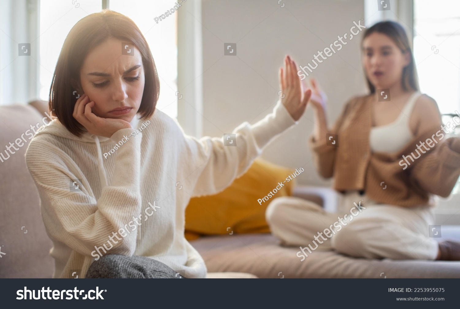 Offended sad european millennial lady ignores screaming displeased girlfriend, making stop sign with hand in living room interior. Scandal, quarrel and relationship problems at home, people emotions #2253955075