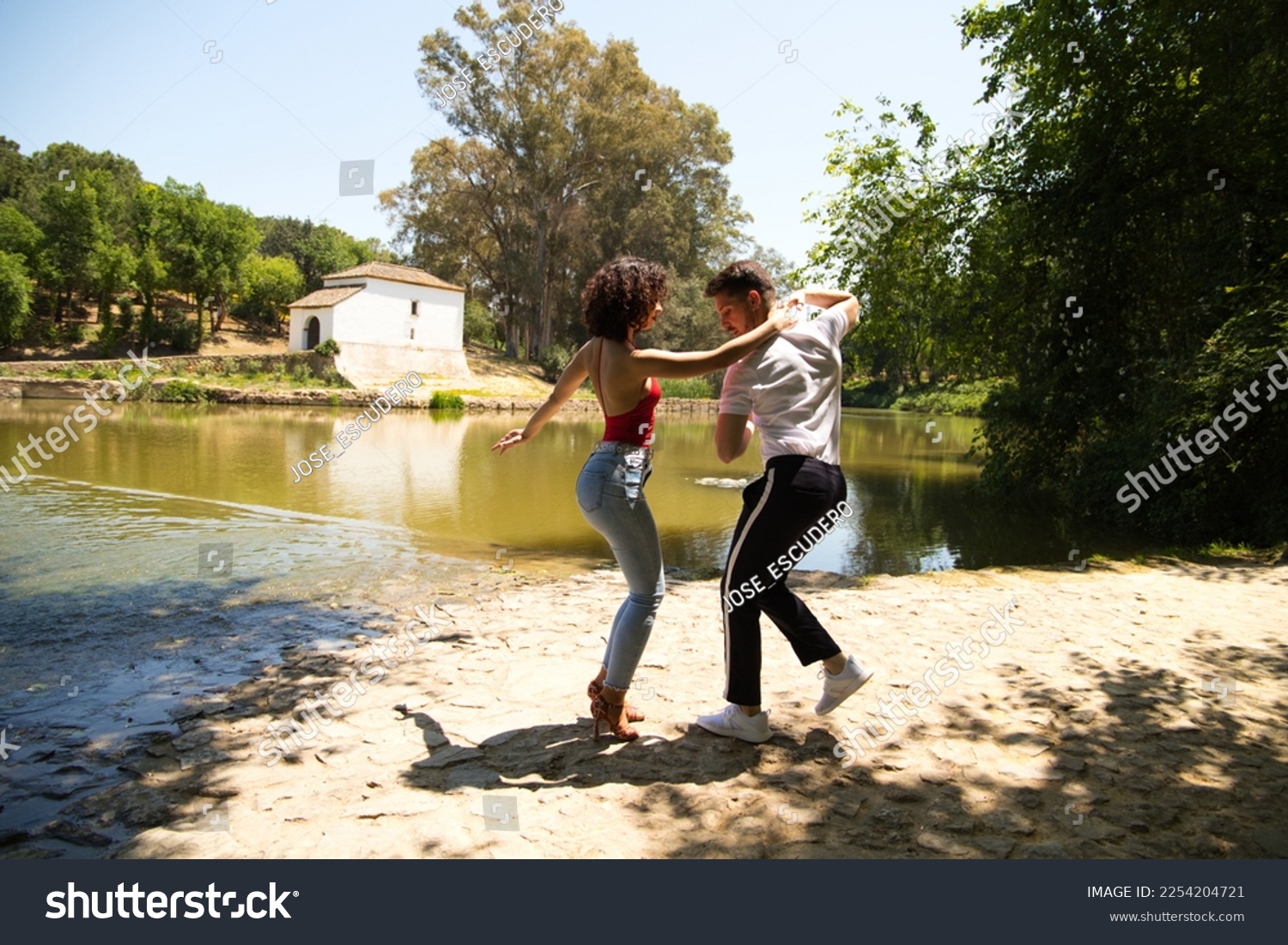 beautiful woman and handsome man latinos dancing bachata are dancing by the river in the forest. The couple do different postures while dancing. Dancing concept and expressions. #2254204721
