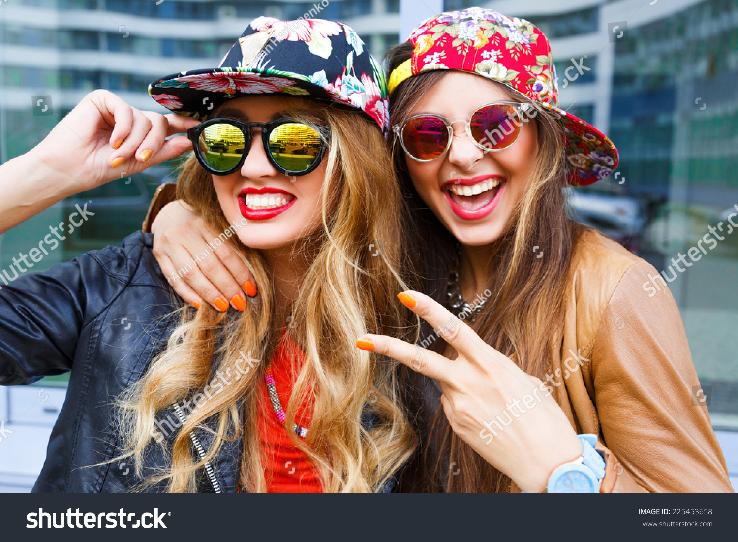 Closeup fashion lifestyle portrait of two pretty best friends girls, wearing bright swag style floral hats, mirrored sunglasses, having fun and make crazy funny faces. Two sisters posing on party. #225453658