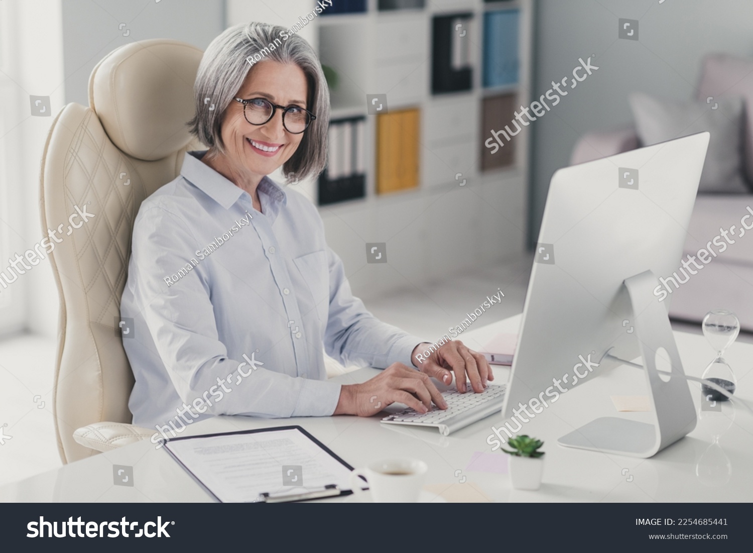 Profile photo of cheerful smart attorney aged lady sit chair keyboard typing email networking office inside #2254685441