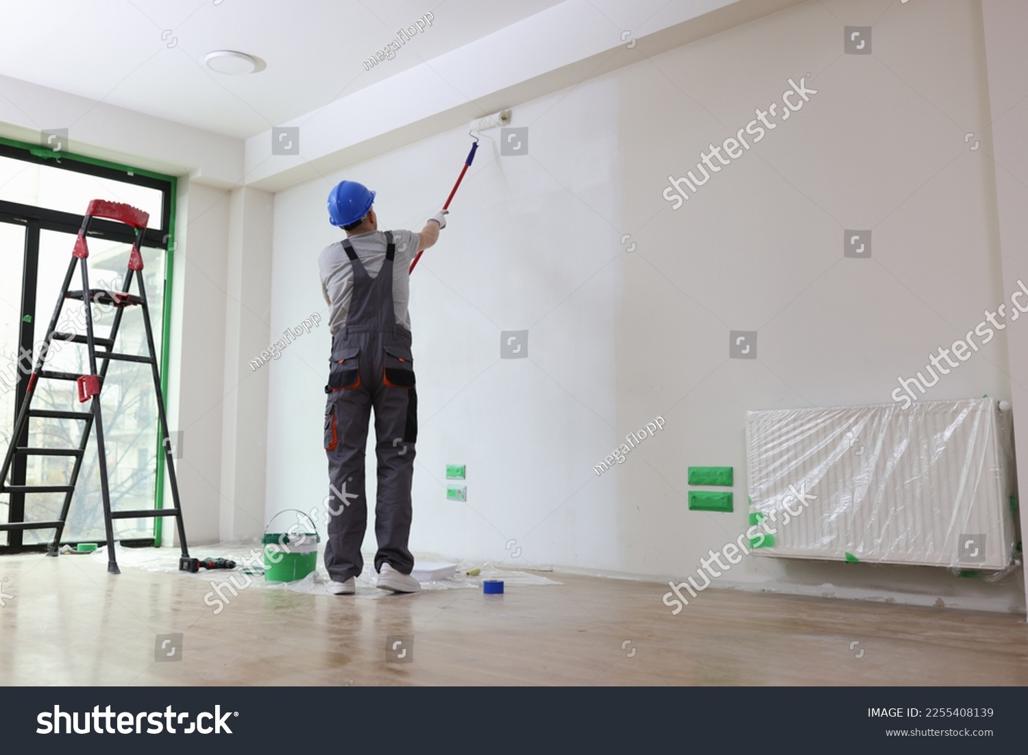 Professional painter paints office wall with roller brush. Decoration and improvement office interior concept. #2255408139