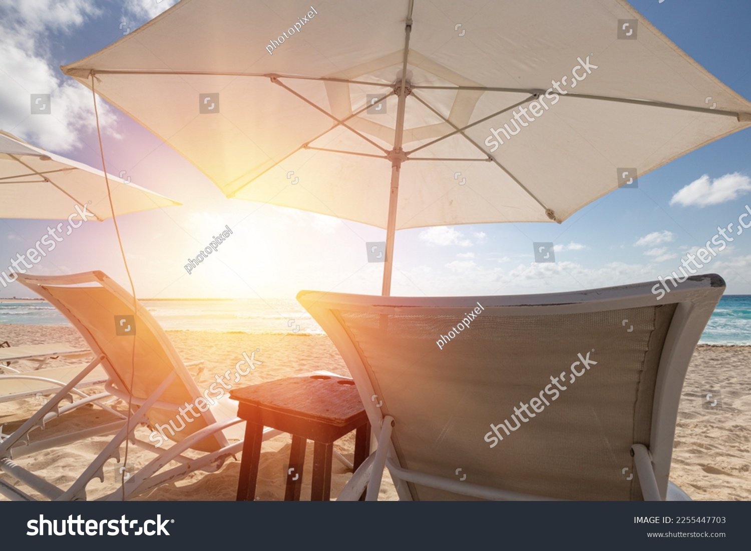 Sun umbrella ans sunbed on white sandy beach with turquoise ocean water. Caribbean sea travel destination. Bounty and pristine nature for vacation. Nobody #2255447703