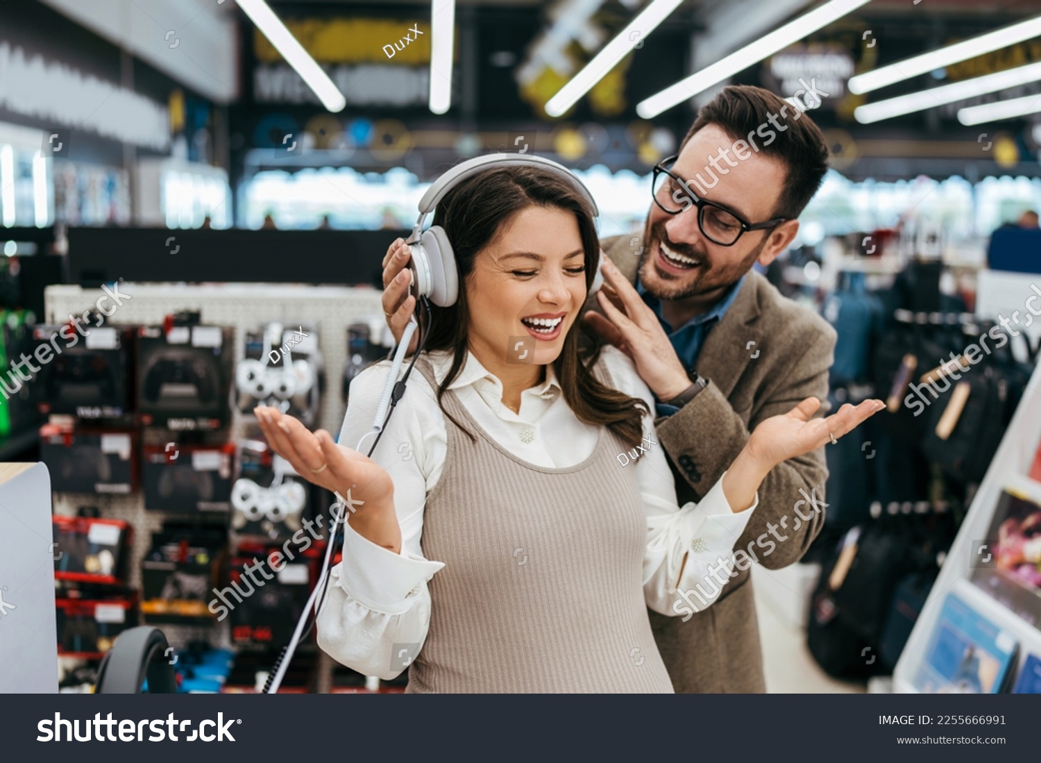Beautiful and happy middle age couple buying consumer tech products in modern home electronics store. They are choosing high quality hifi audio speakers and audiophiles headphones. #2255666991