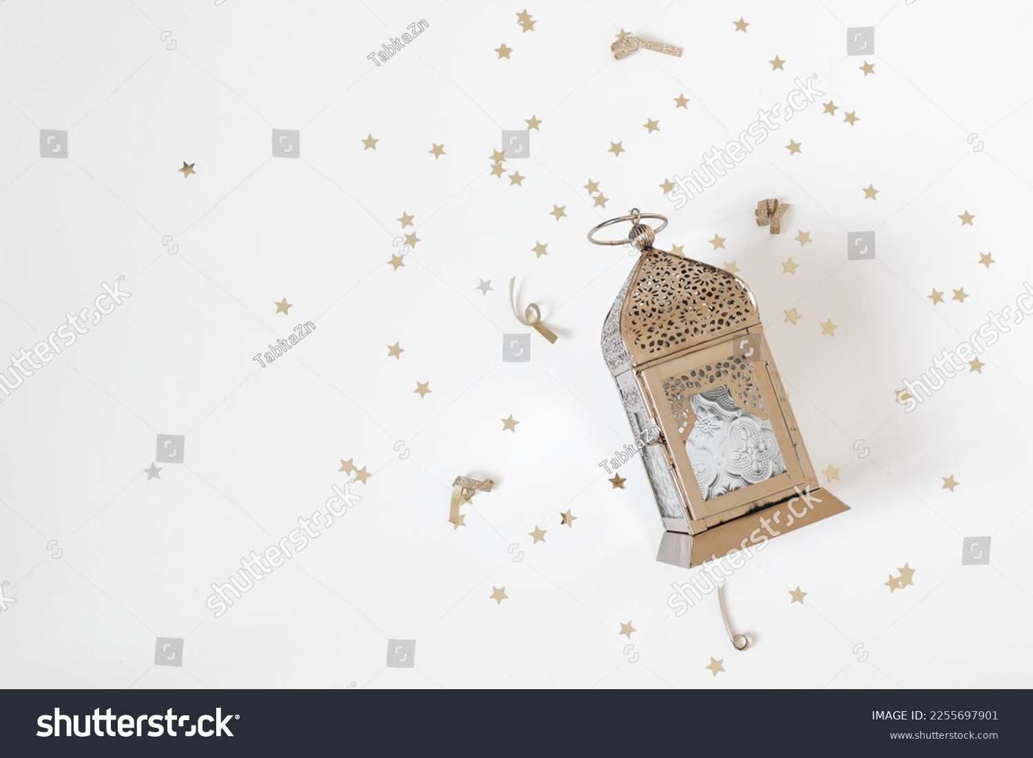 Festive Ramadan holiday composition, web banner. Golden ornamental Moroccan lantern and star shaped confetti isolated on white table background. Iftar party, Eid ul Fitr or Eid al Adha flatlay. Top. #2255697901