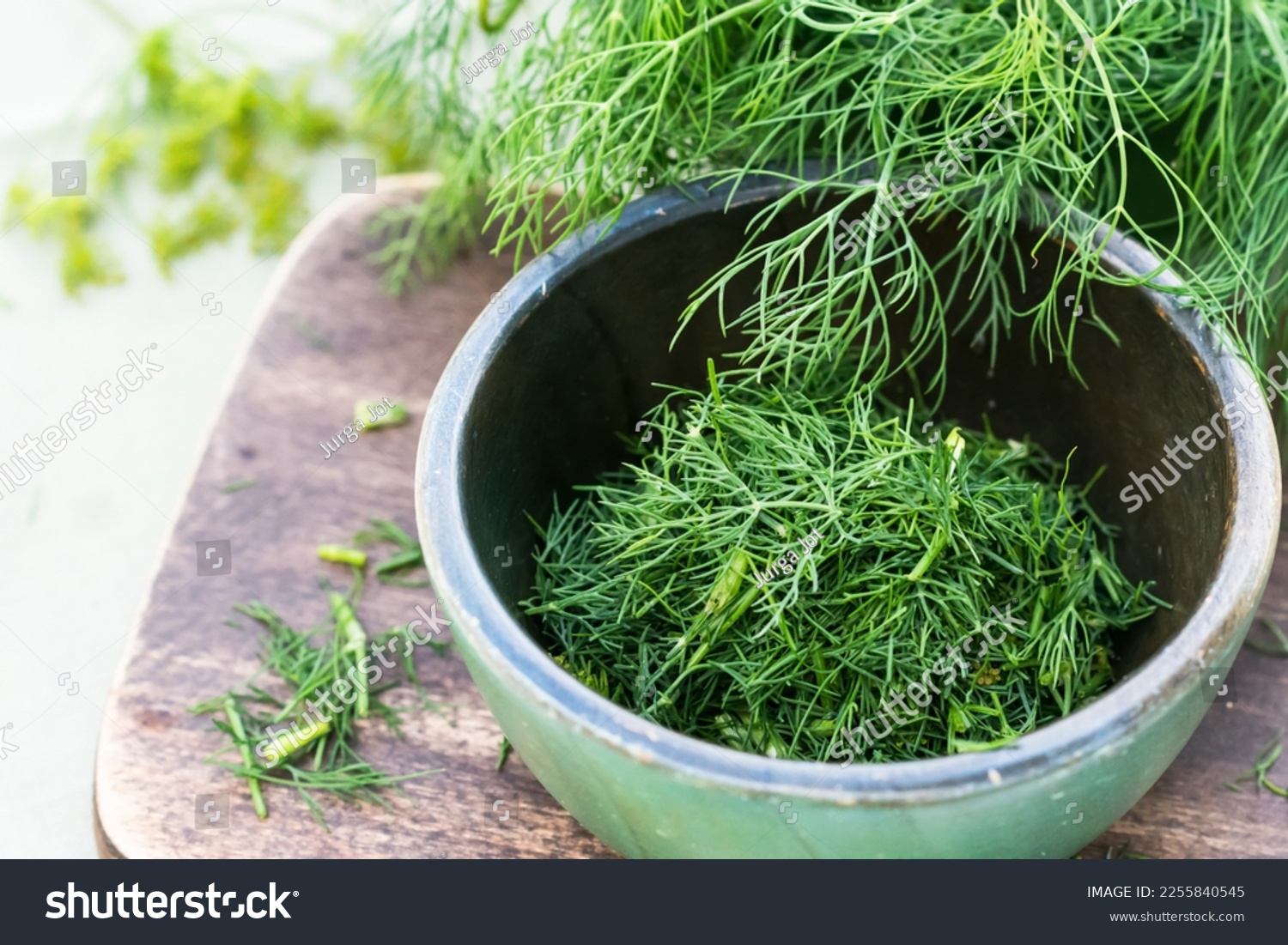 Just harvested cut fresh dills in bowl on brown cutting board on wooden table in summertime, cut dill leaves for flavouring food, flavouring herb concept #2255840545