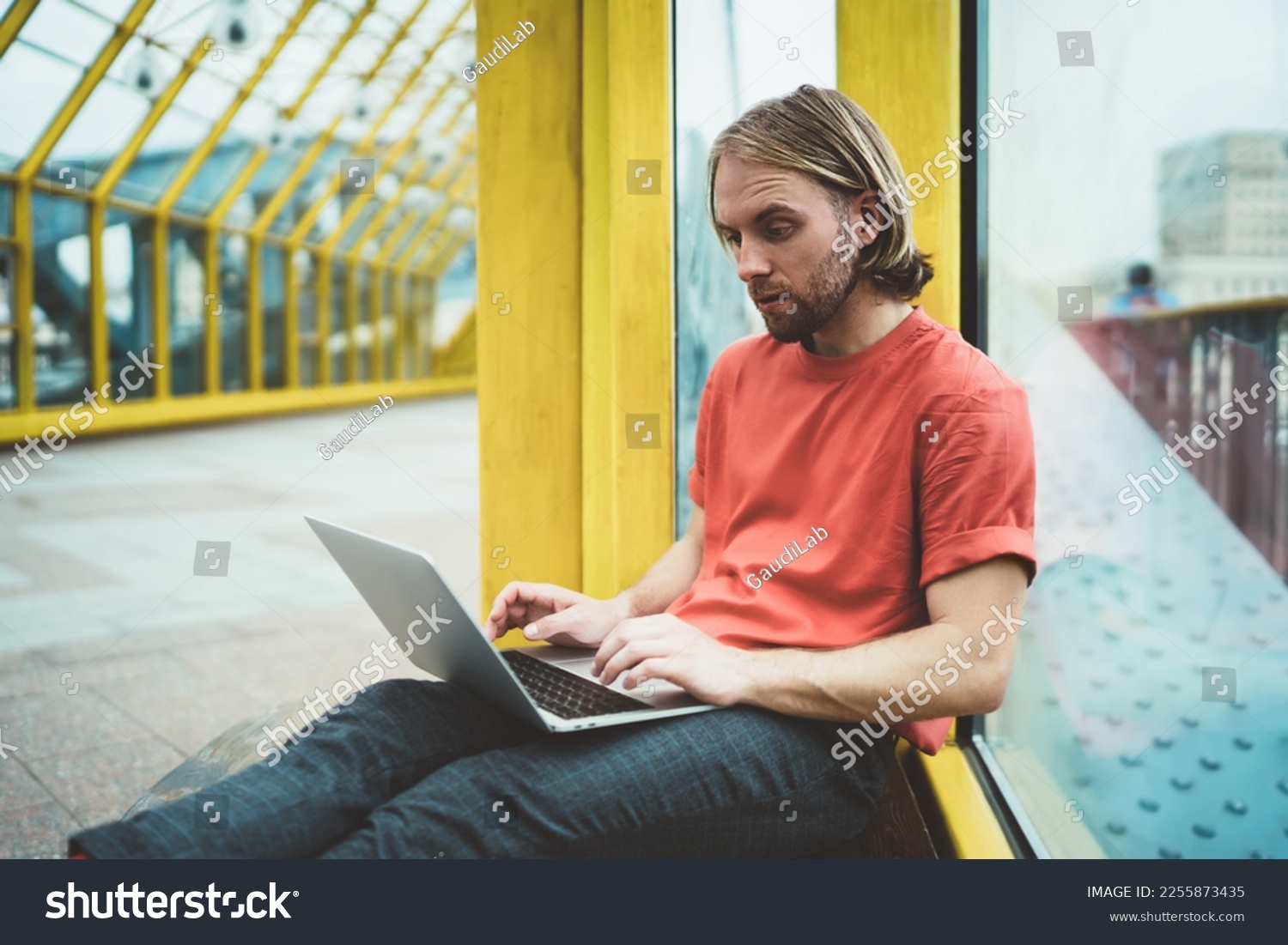 Surprised thoughtful freelancer in casual wear working on startup using laptop looking for decision of problem in covered pedestrian bridge #2255873435