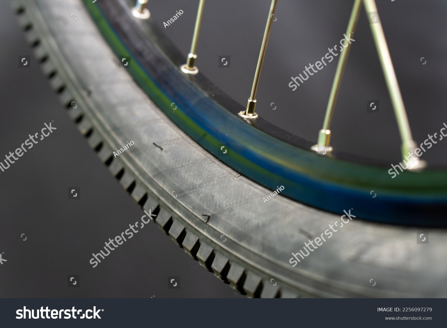 Bicycle tire and wheel close-up on a black background. Abstract background of a wheel in a bicycle workshop. Dirty old worn-out tire. #2256097279