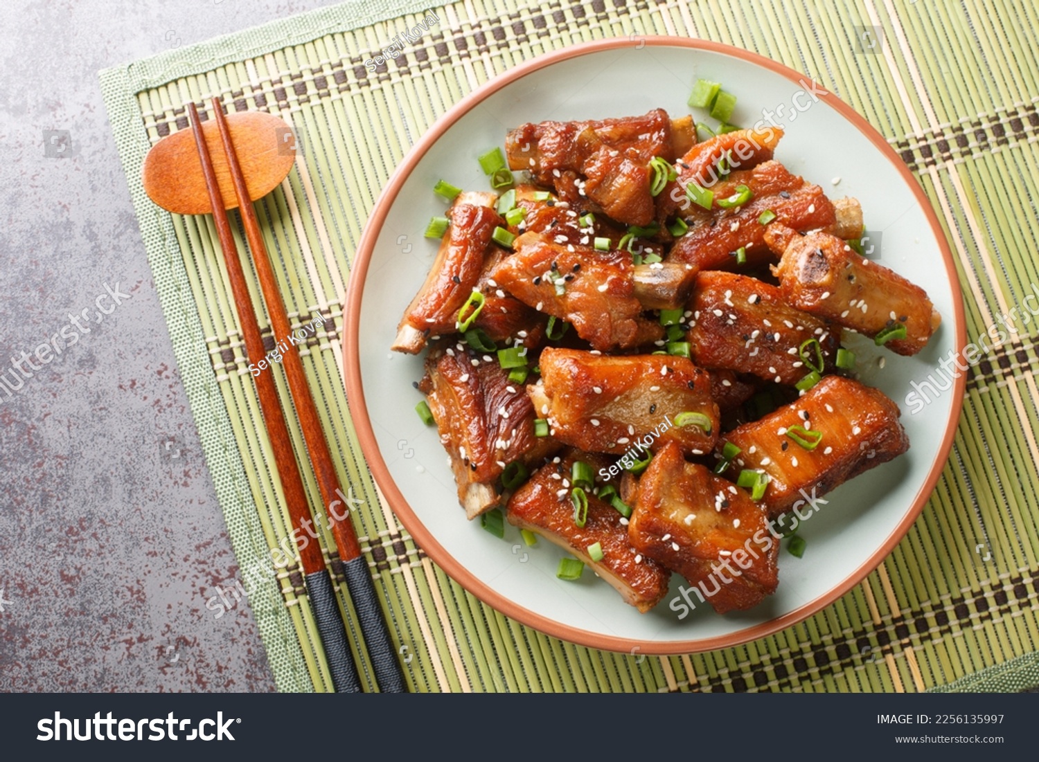 Barbecue sweet and sour spire ribs with green onion and sesame close-up in a plate on the table. Horizontal top view from above
 #2256135997