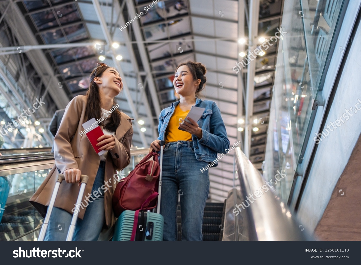 Asian young women passenger walk in airport terminal to boarding gate. Attractive beautiful female tourist friends feeling happy and excited to go travel abroad by airplane for holiday vacation trip. #2256161113