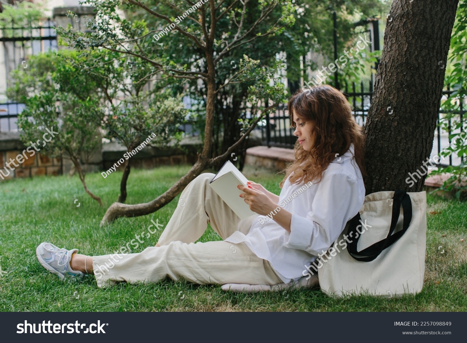Magazine or book image mockup. The girl relaxes on the lawn in the courtyard of the coffee shop, reads a book. #2257098849