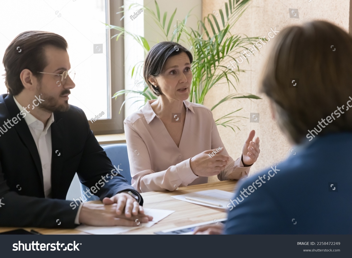 Serious engaged business leader woman talking to colleagues on office meeting, discussing project strategy, telling ideas, offering solutions, problem solving, sitting at table #2258472249