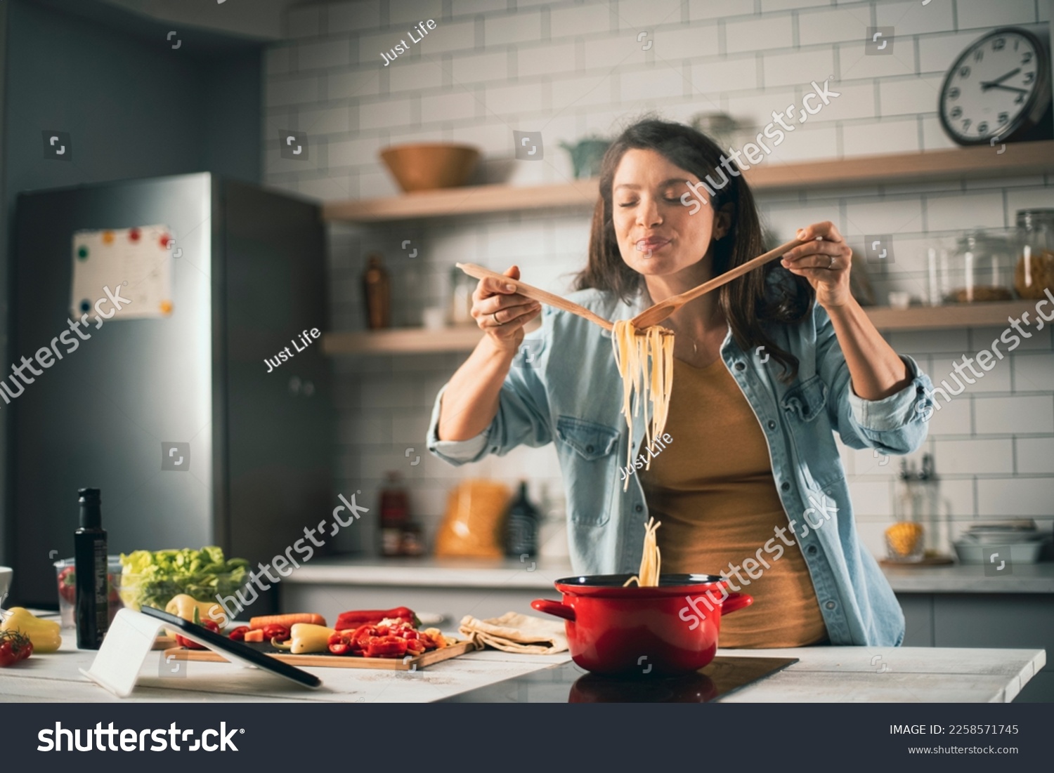 Beautiful pregnant woman preparing delicious food. Smiling woman cooking at home.	 #2258571745