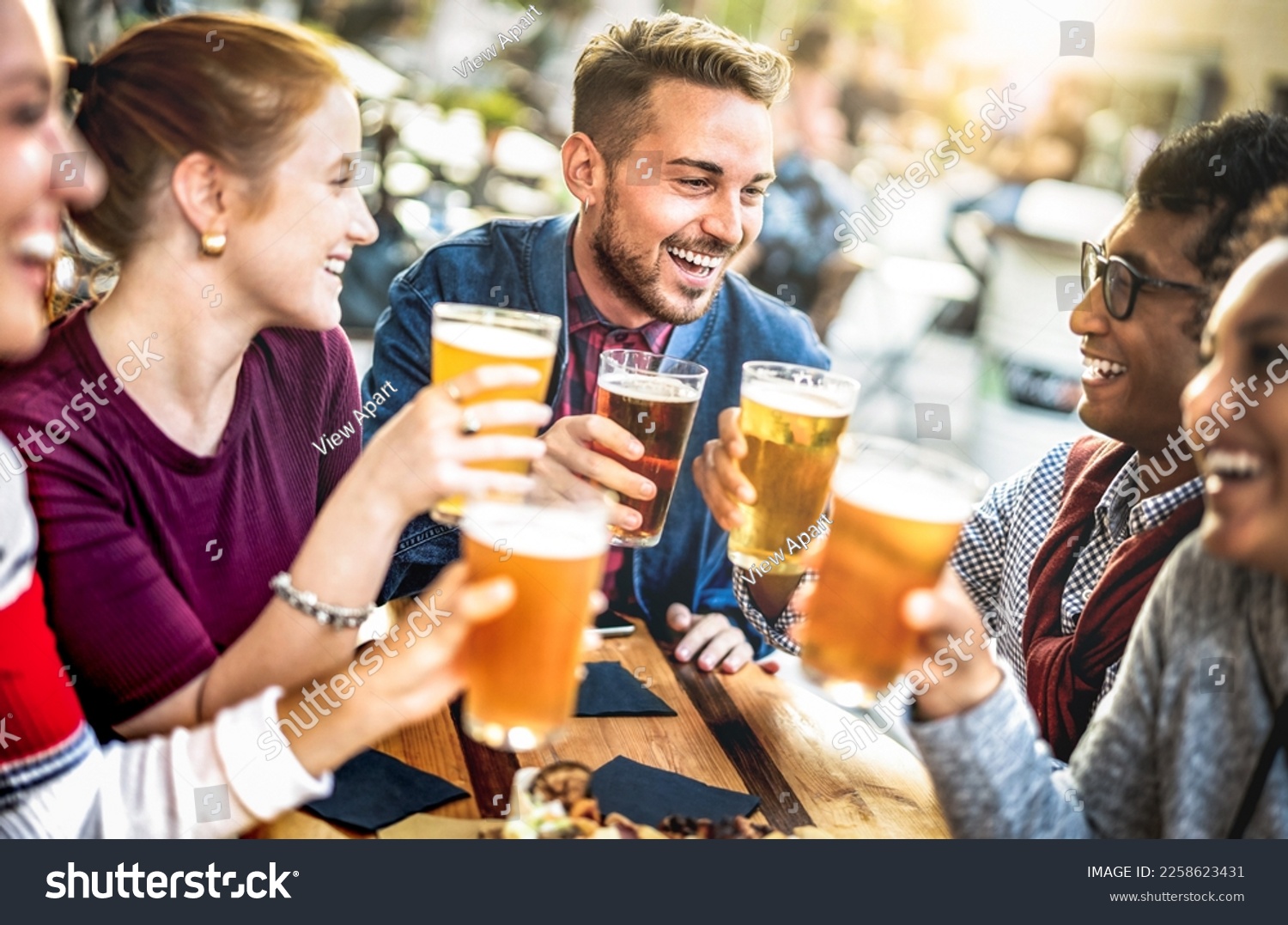 Young people drinking beer pints at brewery bar garden - Genuine beverage life style concept with guys and girls sharing happy hour together at open air pub dehor - Warm sunset backlight filter #2258623431