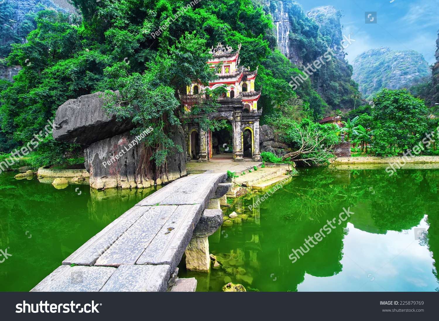 Outdoor park landscape with lake and stone bridge. Gate entrance to ancient Bich Dong pagoda complex. Ninh Binh, Vietnam travel destination #225879769