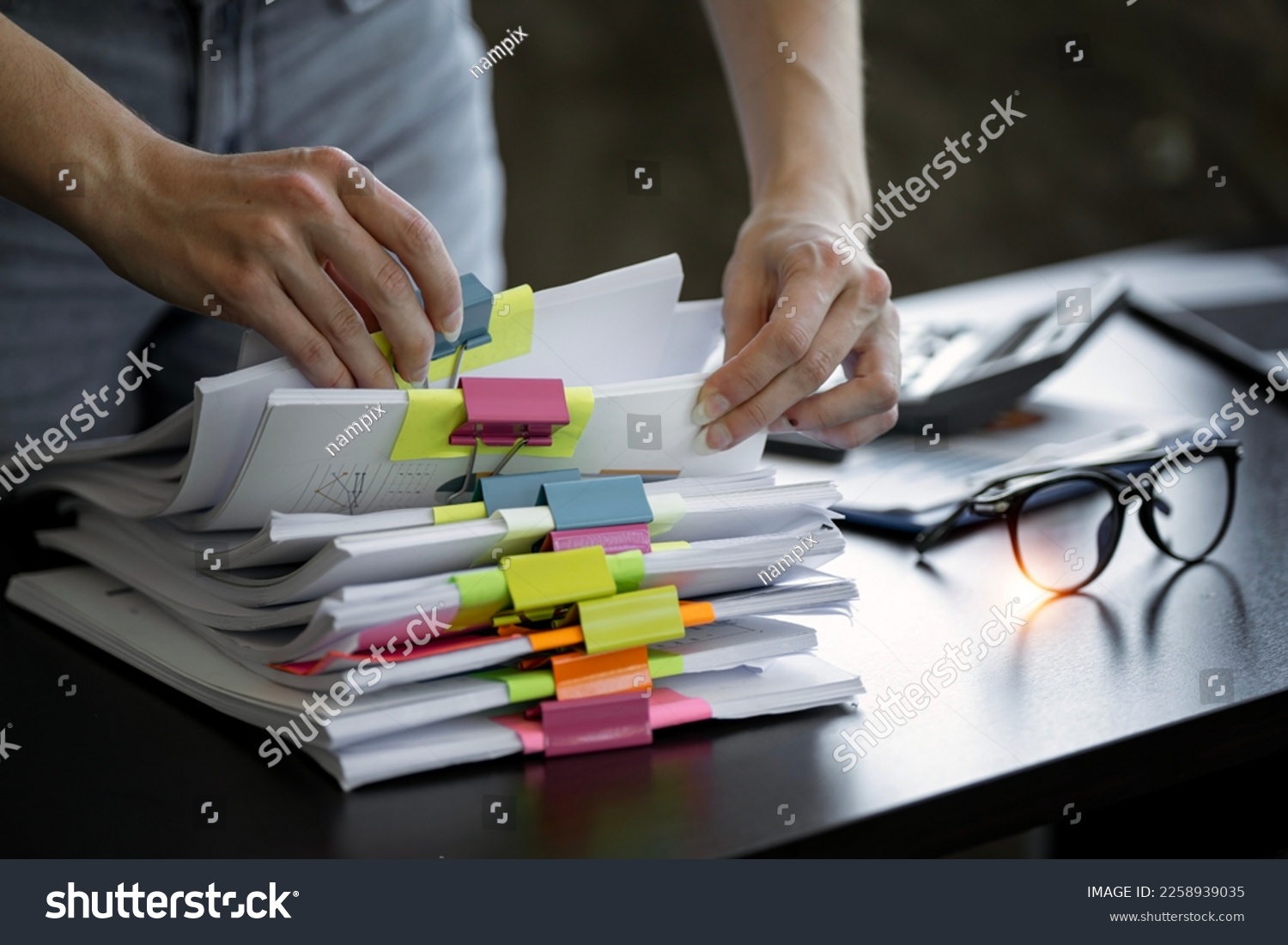 Businesswoman hands working in Stacks of paper files for searching and checking unfinished document achieves on folders papers #2258939035