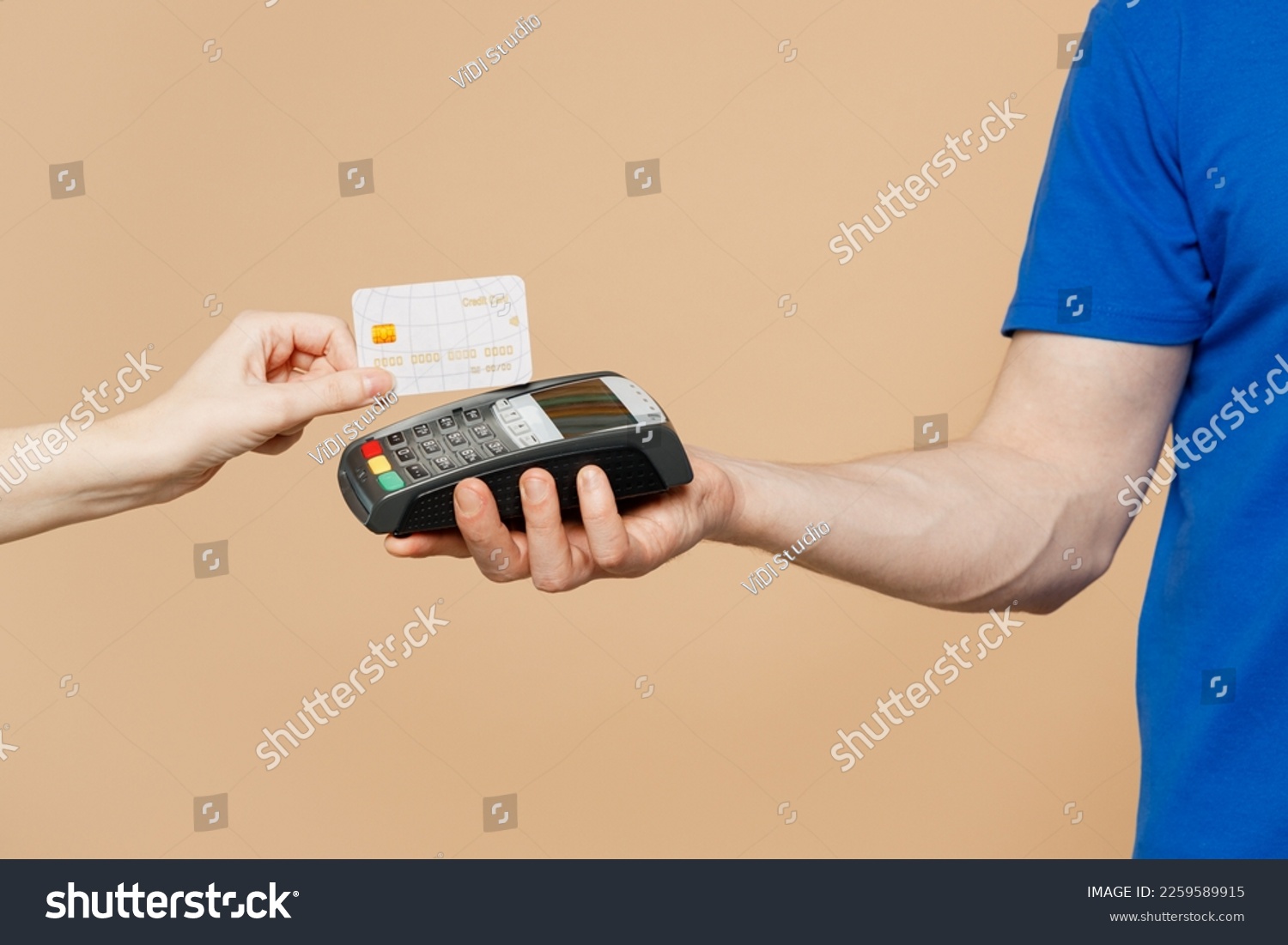 Close up cropped delivery guy employee man hold in hand hold bank payment terminal to process acquire credit card isolated on pastel plain light pastel beige wall background. Copy space advertising #2259589915