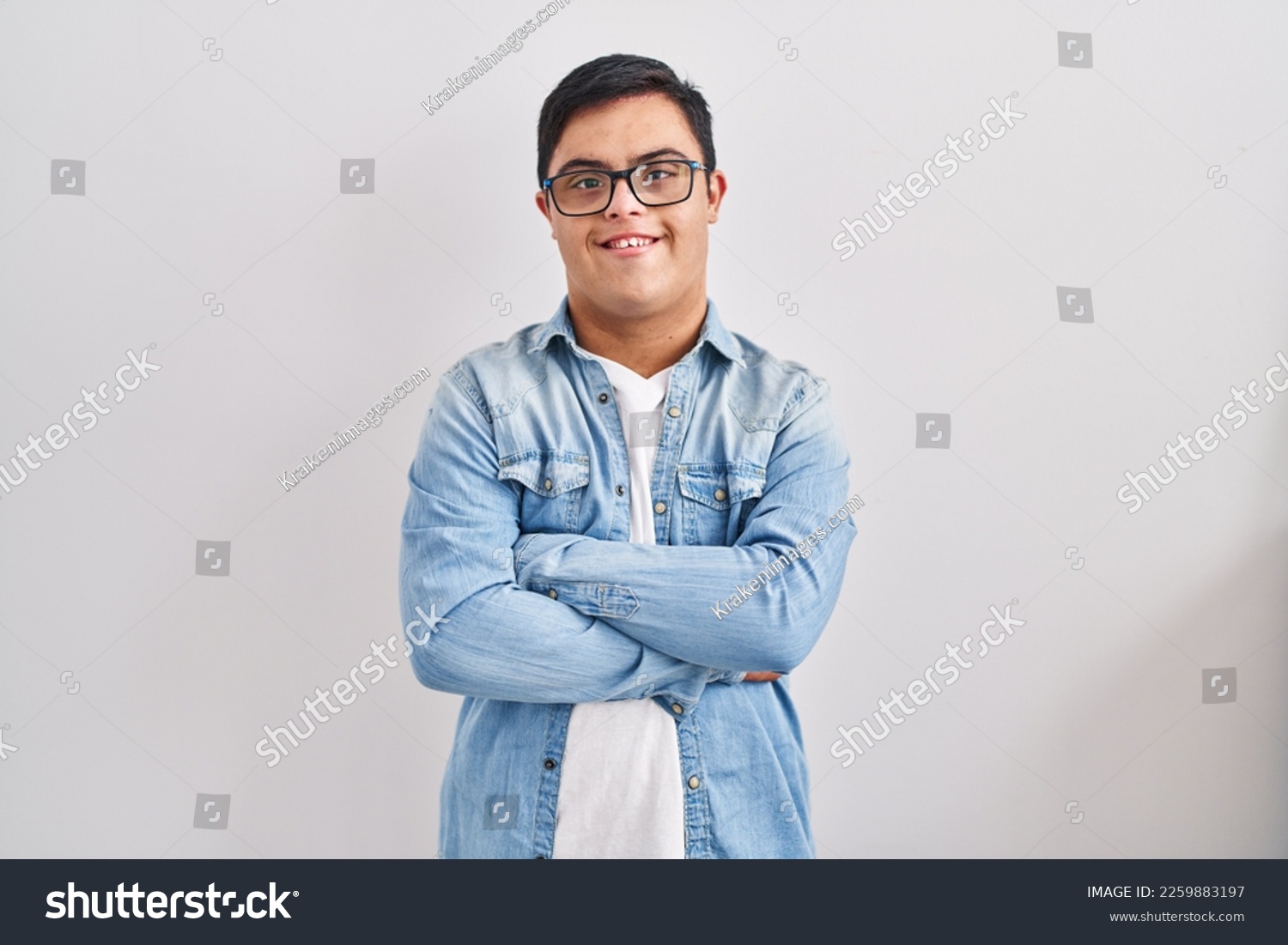 Young hispanic man with down syndrome wearing casual denim jacket over white background happy face smiling with crossed arms looking at the camera. positive person.  #2259883197