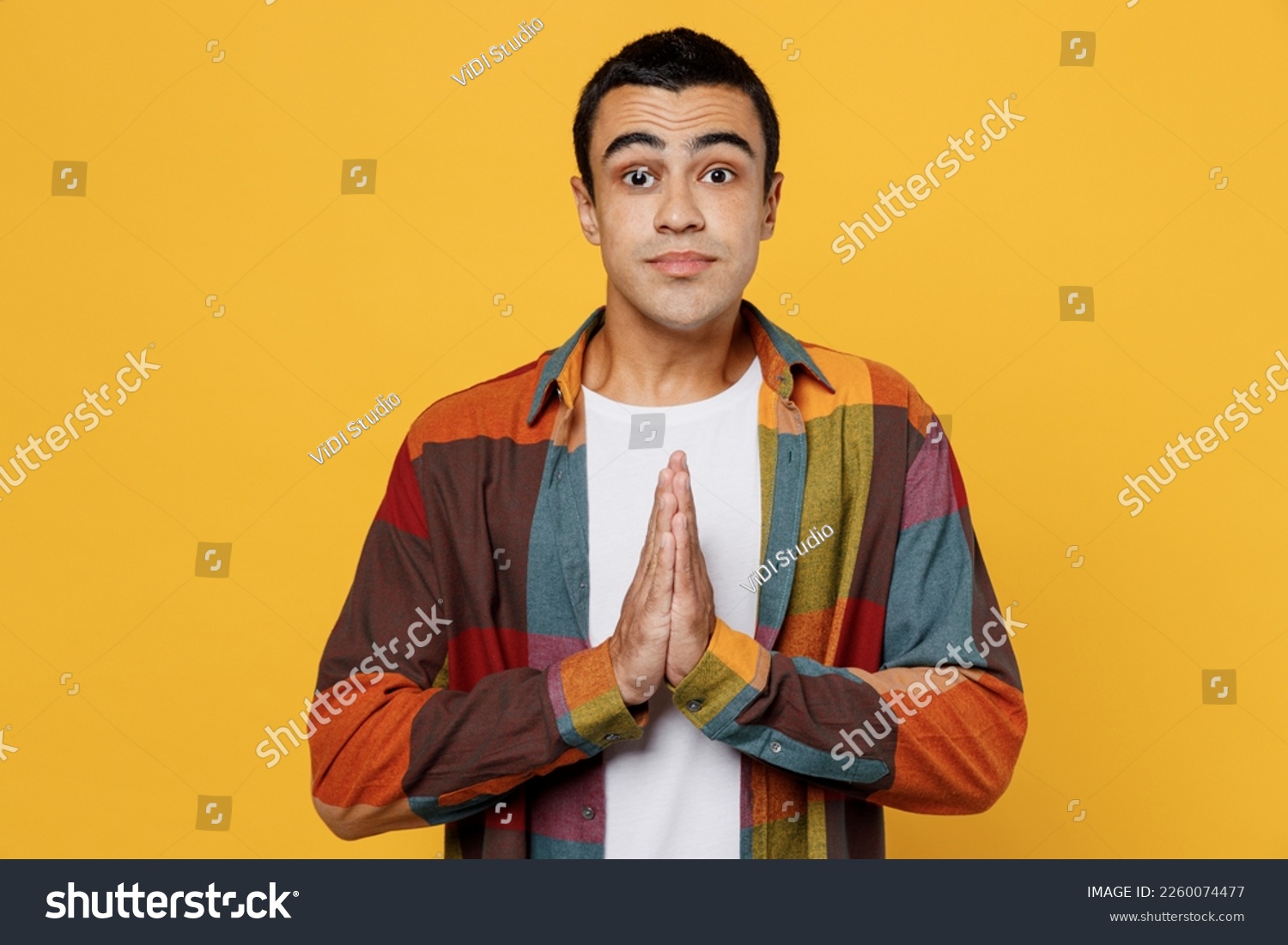 Young middle eastern man 20s wear casual shirt white t-shirt hold hands folded in prayer gesture, begging about something isolated on plain yellow background studio portrait People lifestyle concept #2260074477
