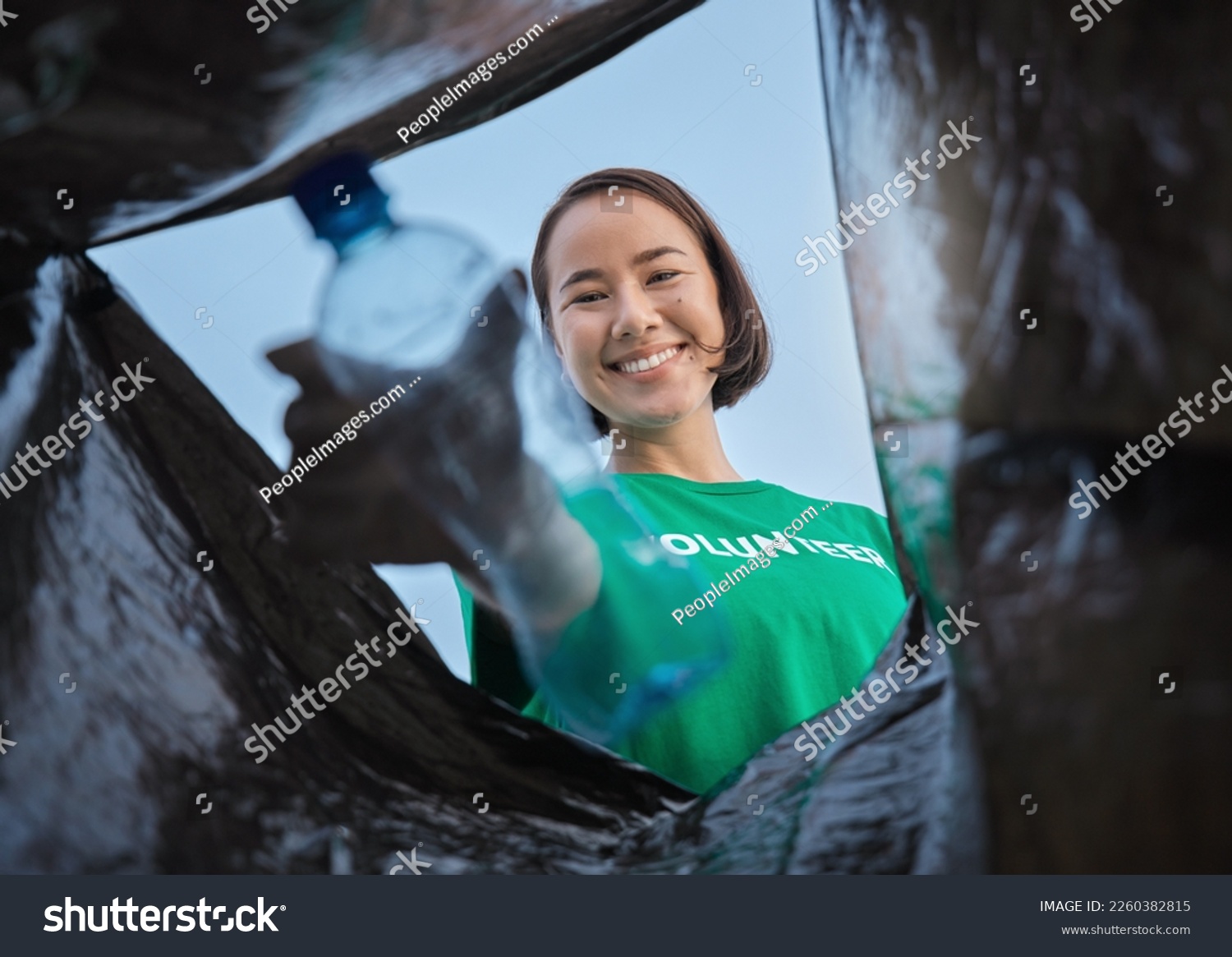 Recycle, bottle and asian woman with view in bag, sustainability and cleaning plastic pollution, earth day and help with community. Saving the environment, charity and people putting trash in garbage #2260382815