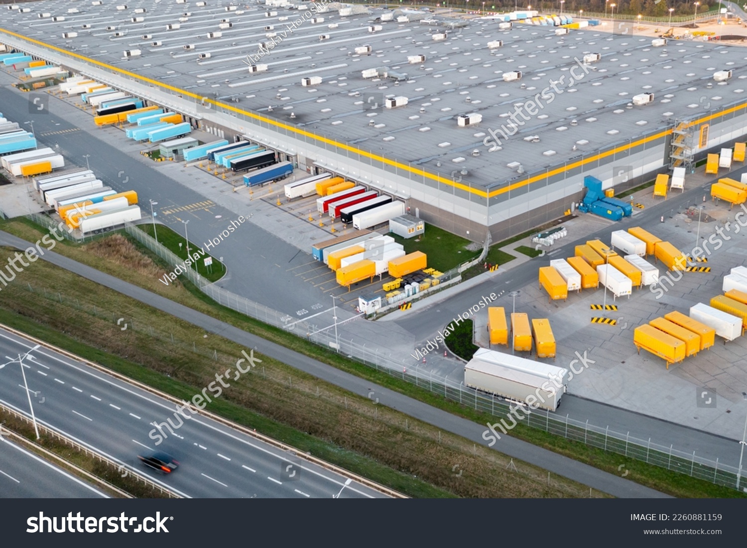 Many large semi-trailers are parked next to the logistics warehouse, waiting to be loaded for transport around the country. #2260881159