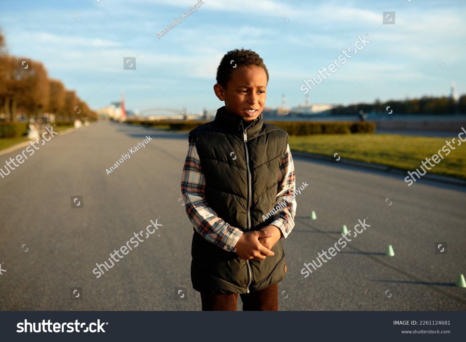 Upset worried black boy kid standing on background with city park holding his stomach with painful facial expression and miserable look, feeling pain in belly after training outdoor #2261124681