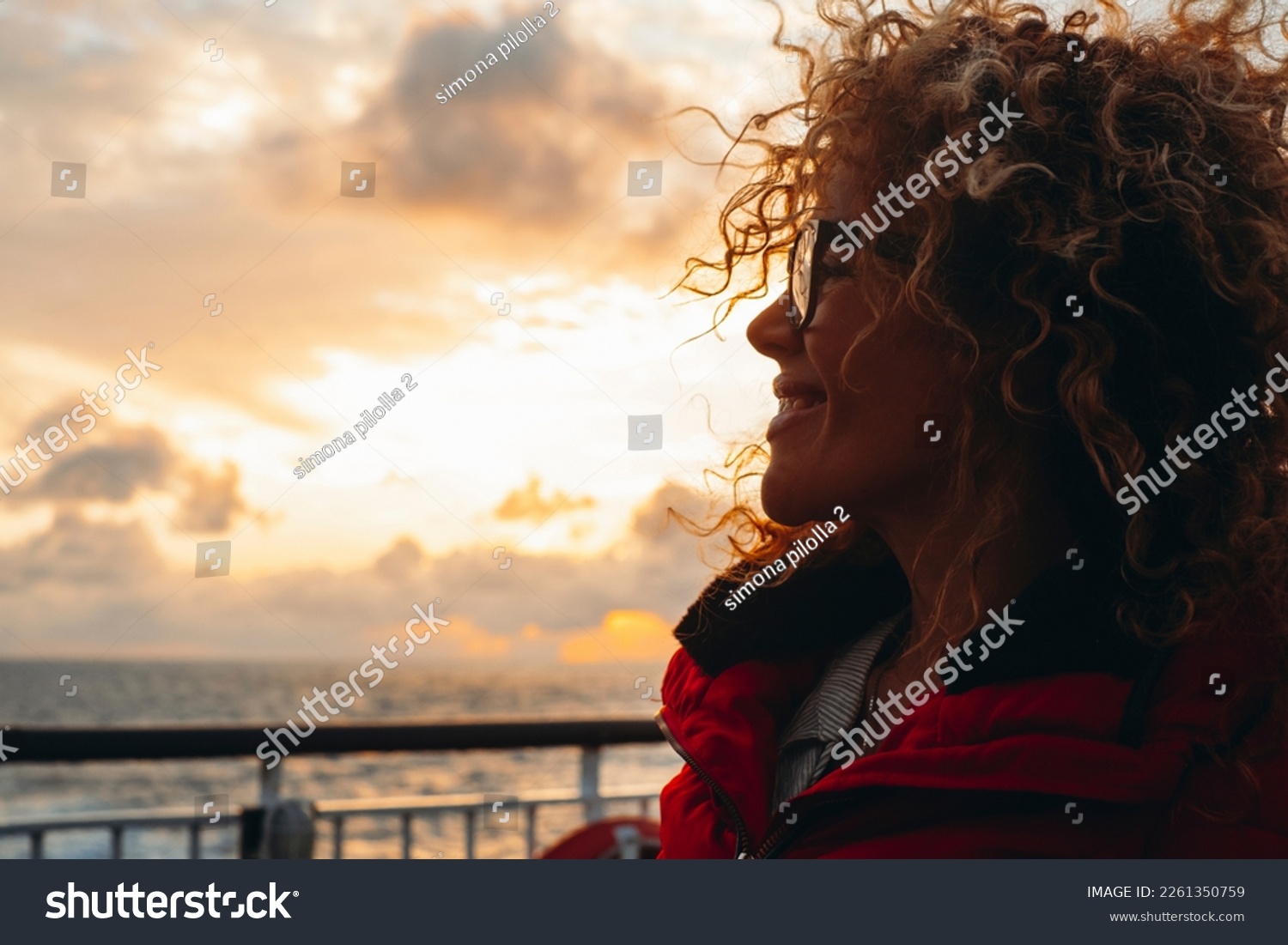 Travel and happiness expression side portrait concept. One woman smiling and enjoying freedom. Traveler tourist young lady with sunset and ocean in background. Ferry cruise boat ship transport. Sun #2261350759