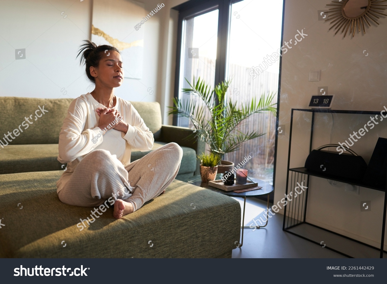 Woman meditating at home with eyes closed  #2261442429