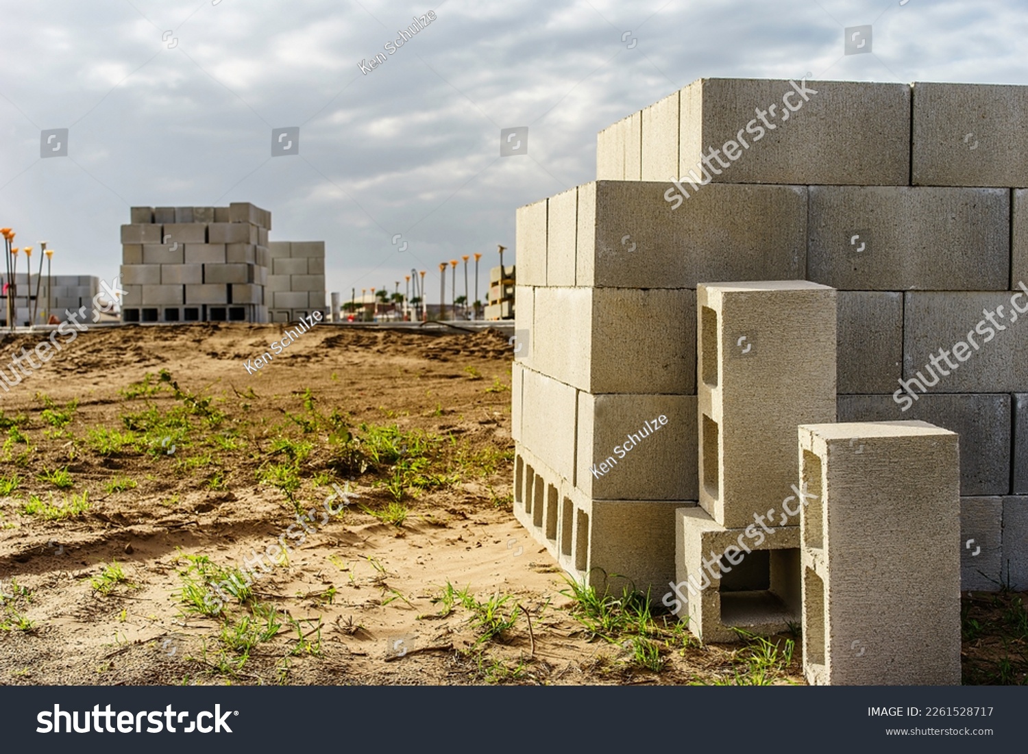 Stack of concrete blocks (foreground focus) on sandy lot for construction of a single-family house in a suburban residential development in southwest Florida #2261528717