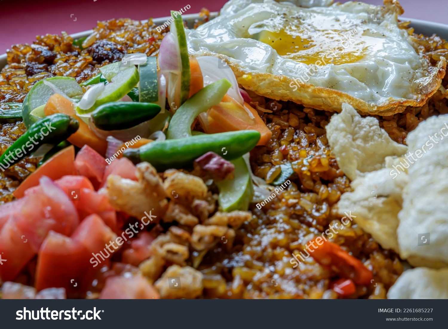 close up view of fried rice in a cafe, you can see some of the toppings that complement the menu such as eggs, chips and vegetables #2261685227