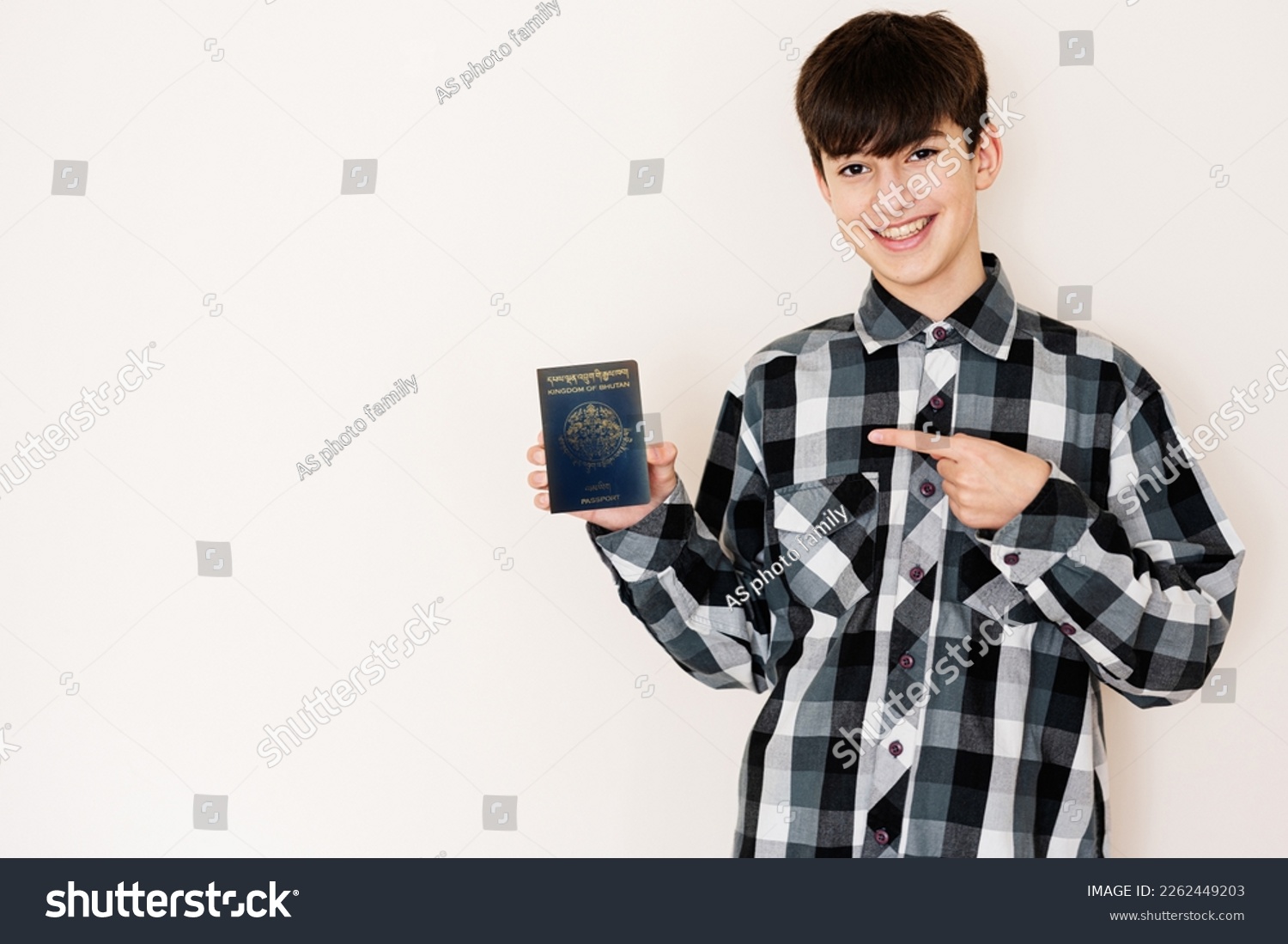 Young teenager boy holding Bhutan passport looking positive and happy standing and smiling with a confident smile against white background. #2262449203